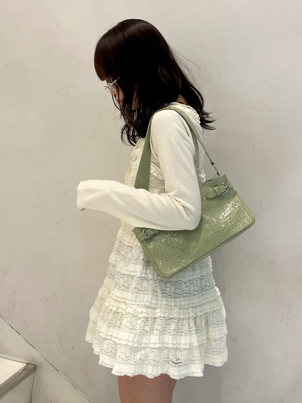 ホワイト系のワンピース、ホワイト系のニット/セーター、グリーン系のハンドバッグを着用したレディースの冬コーディネートの6枚目の写真