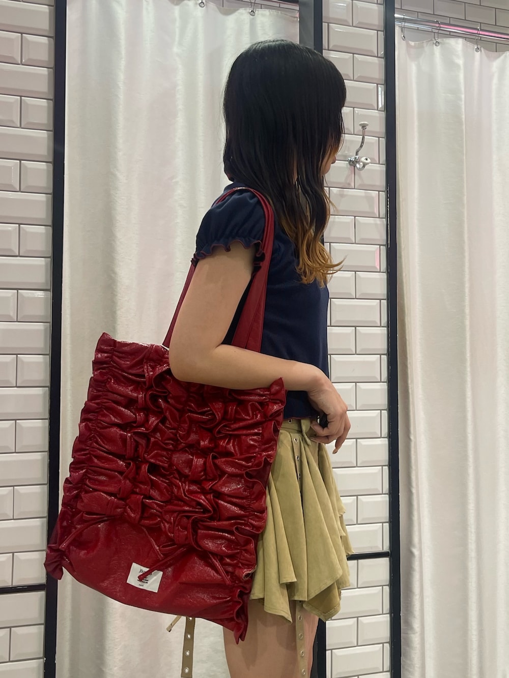 ベージュ系のスカート、ブルー系のポロシャツ、レッド系のトートバッグを着用したレディースの夏コーディネートの5枚目の写真