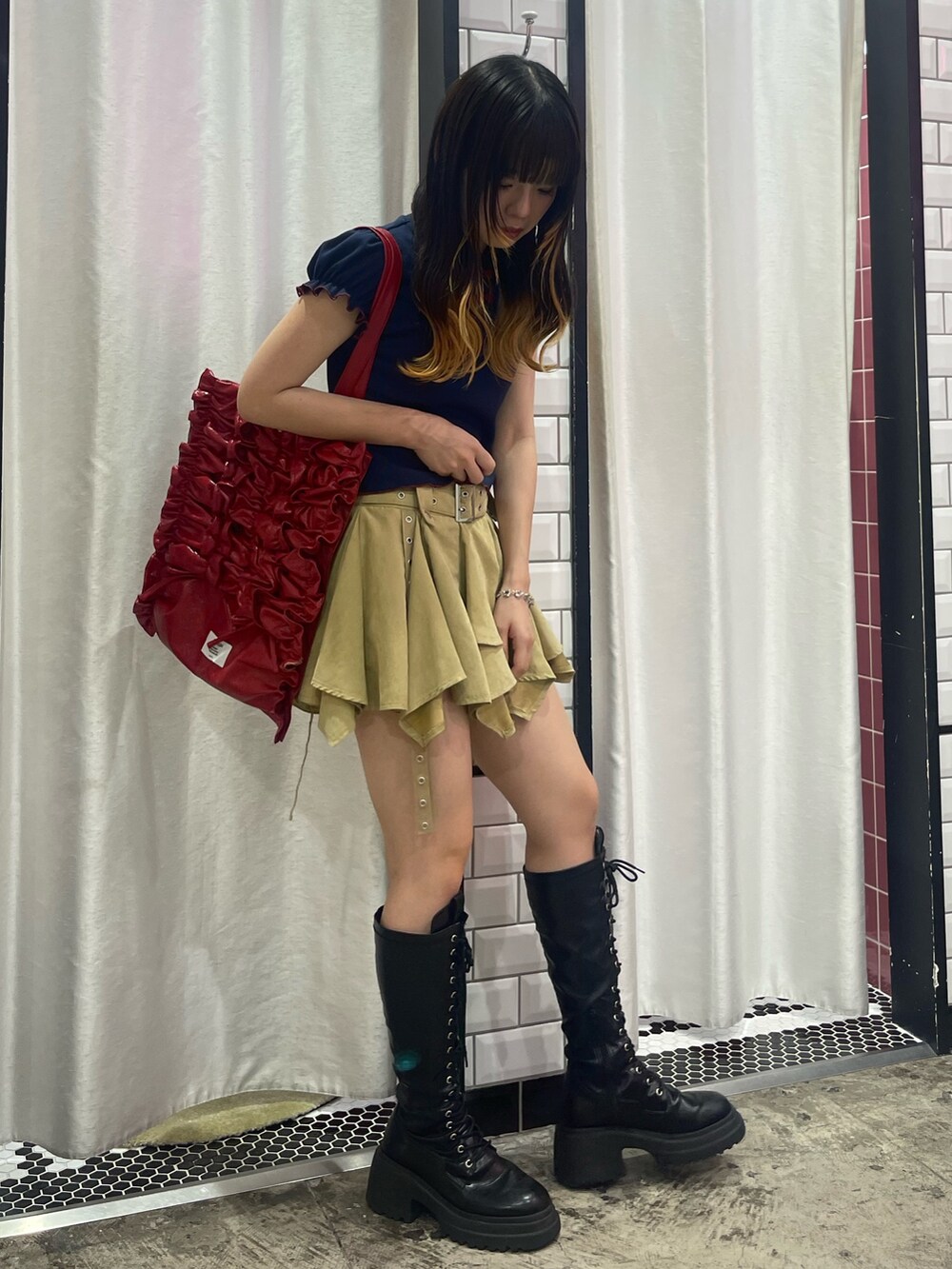 ベージュ系のスカート、ブルー系のポロシャツ、レッド系のトートバッグを着用したレディースの夏コーディネートの2枚目の写真