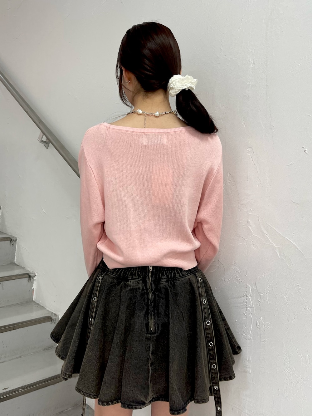 ピンク系のニット/セーター、ブラック系のデニムスカート、ブラック系のブーツを着用したレディースの春コーディネートの7枚目の写真