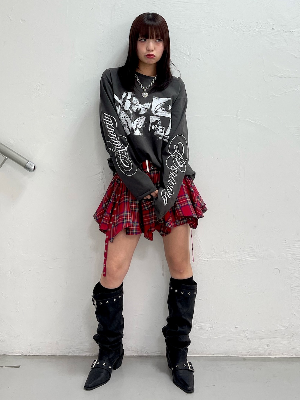 ブラック系のTシャツ/カットソー、レッド系のスカート、ブラック系のブーツを着用したレディースの冬コーディネートの2枚目の写真