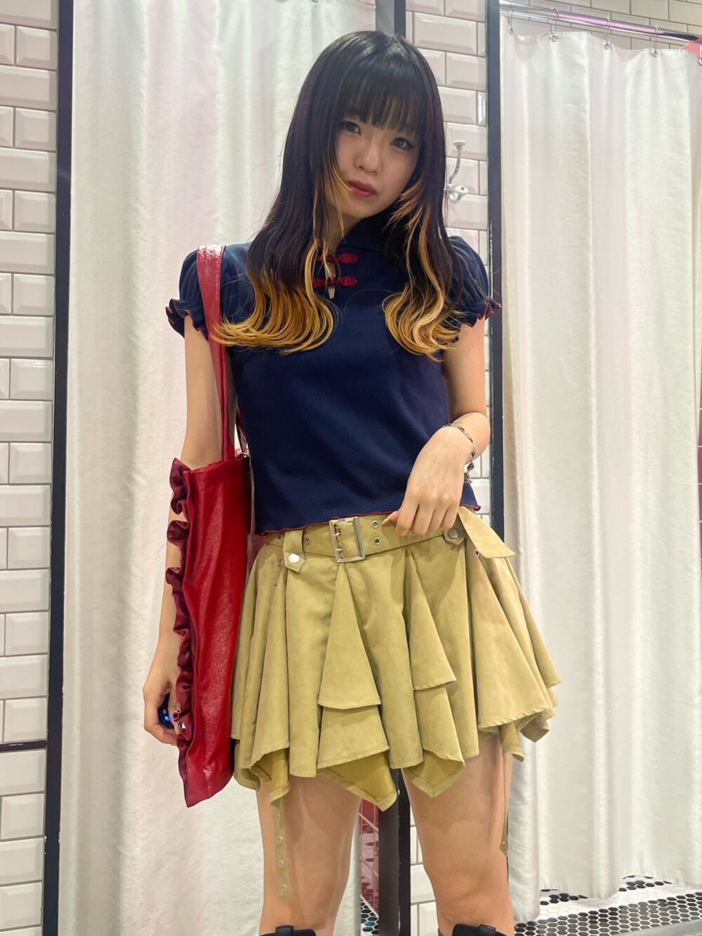 ベージュ系のスカート、ブルー系のポロシャツ、レッド系のトートバッグを着用したレディースの夏コーディネートの4枚目の写真