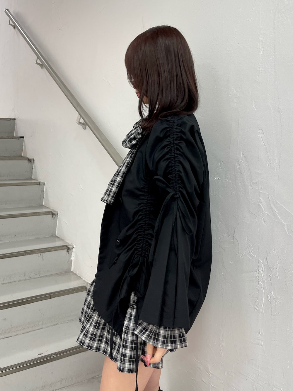 ブラック系のテーラードジャケット、ブラック系のワンピース、ブラック系のブーツを着用したレディースの冬コーディネートの6枚目の写真