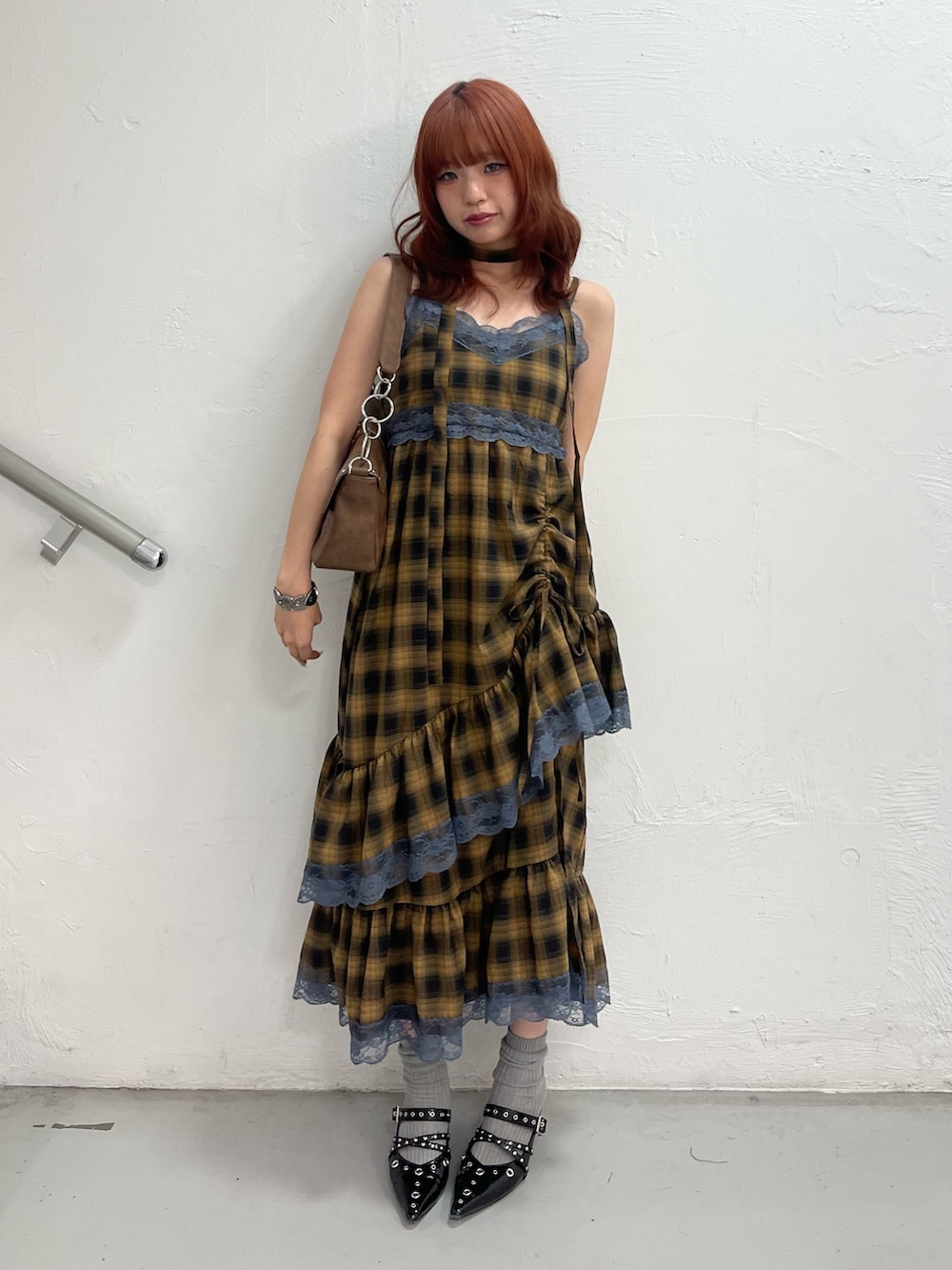 イエロー系のワンピース、ブラック系のパンプス、ブラウン系のハンドバッグを着用したレディースの夏コーディネートの2枚目の写真