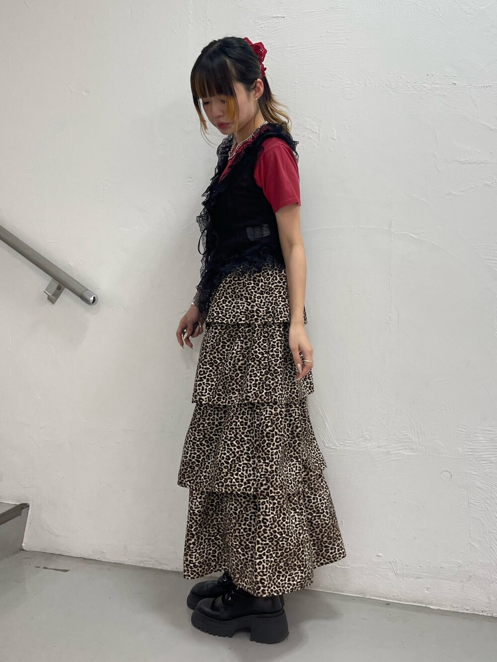 ブラウン系のスカート、ブラック系のブーツ、ブラック系のベストを着用したレディースの夏コーディネートの2枚目の写真