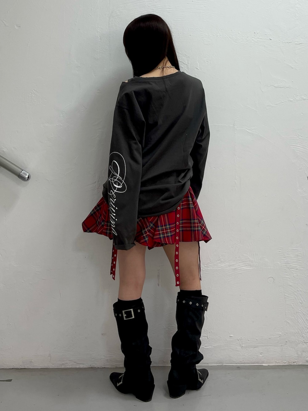 ブラック系のTシャツ/カットソー、レッド系のスカート、ブラック系のブーツを着用したレディースの冬コーディネートの4枚目の写真