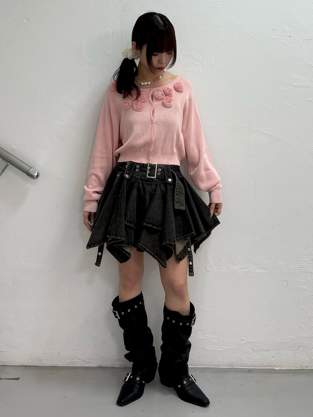 ピンク系のニット/セーター、ブラック系のデニムスカート、ブラック系のブーツを着用したレディースの春コーディネートの2枚目の写真