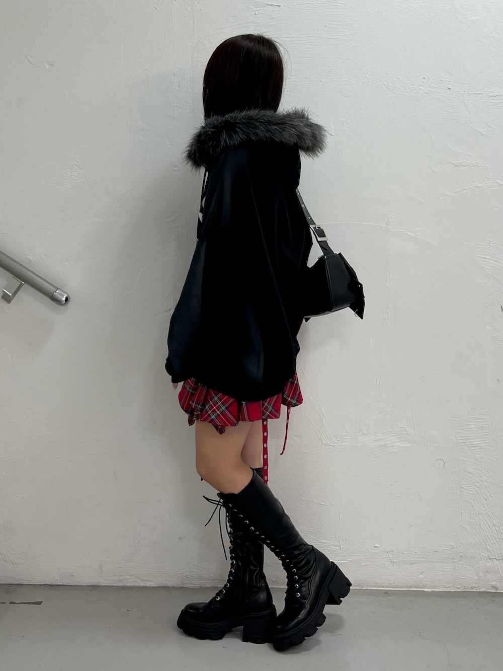 ブラック系のパーカー、レッド系のスカート、ブラック系のショルダーバッグを着用したレディースの冬コーディネートの2枚目の写真