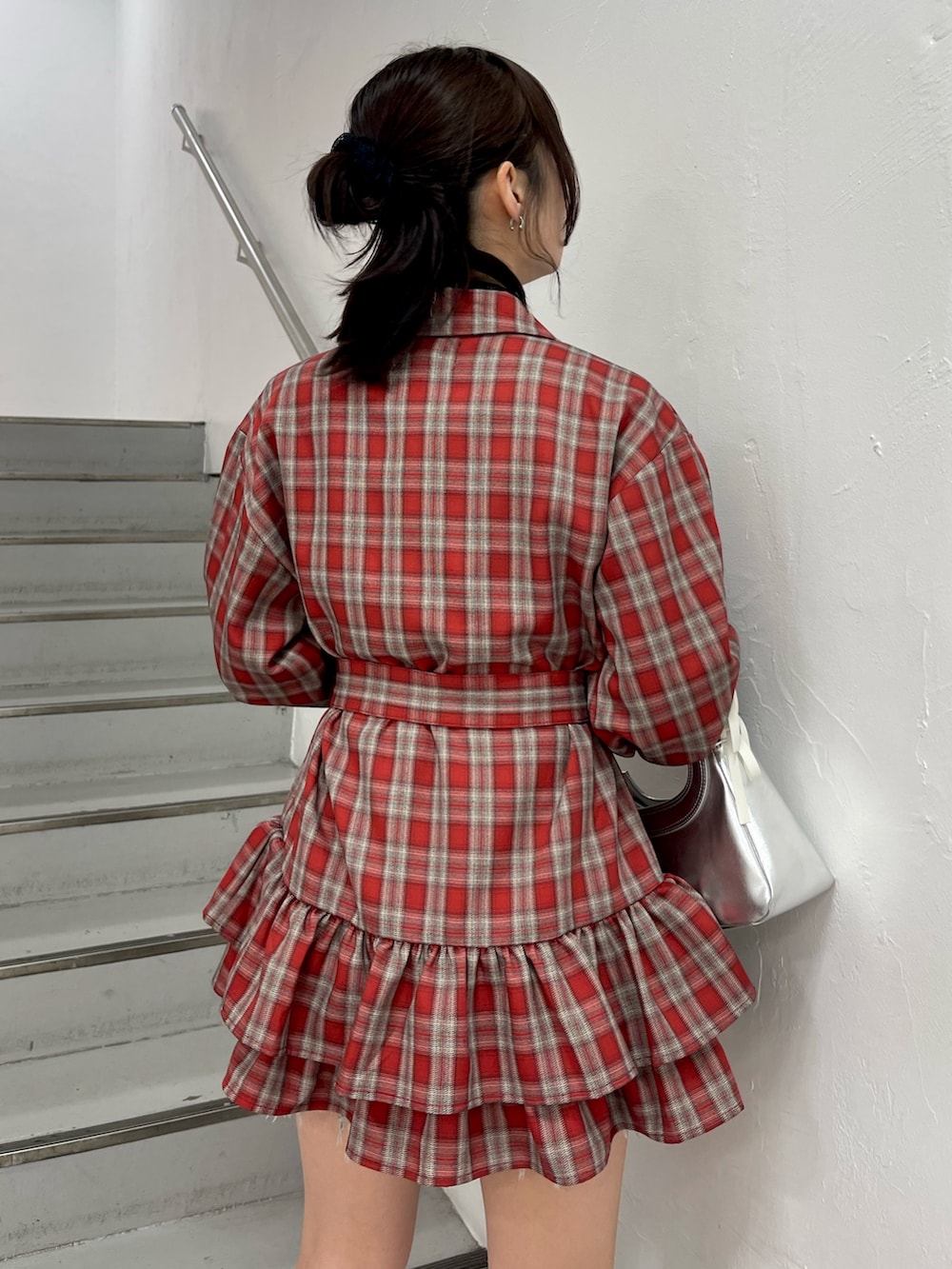 レッド系のワンピース、シルバー系のハンドバッグ、ブラック系のニット/セーターを着用したレディースの冬コーディネートの7枚目の写真