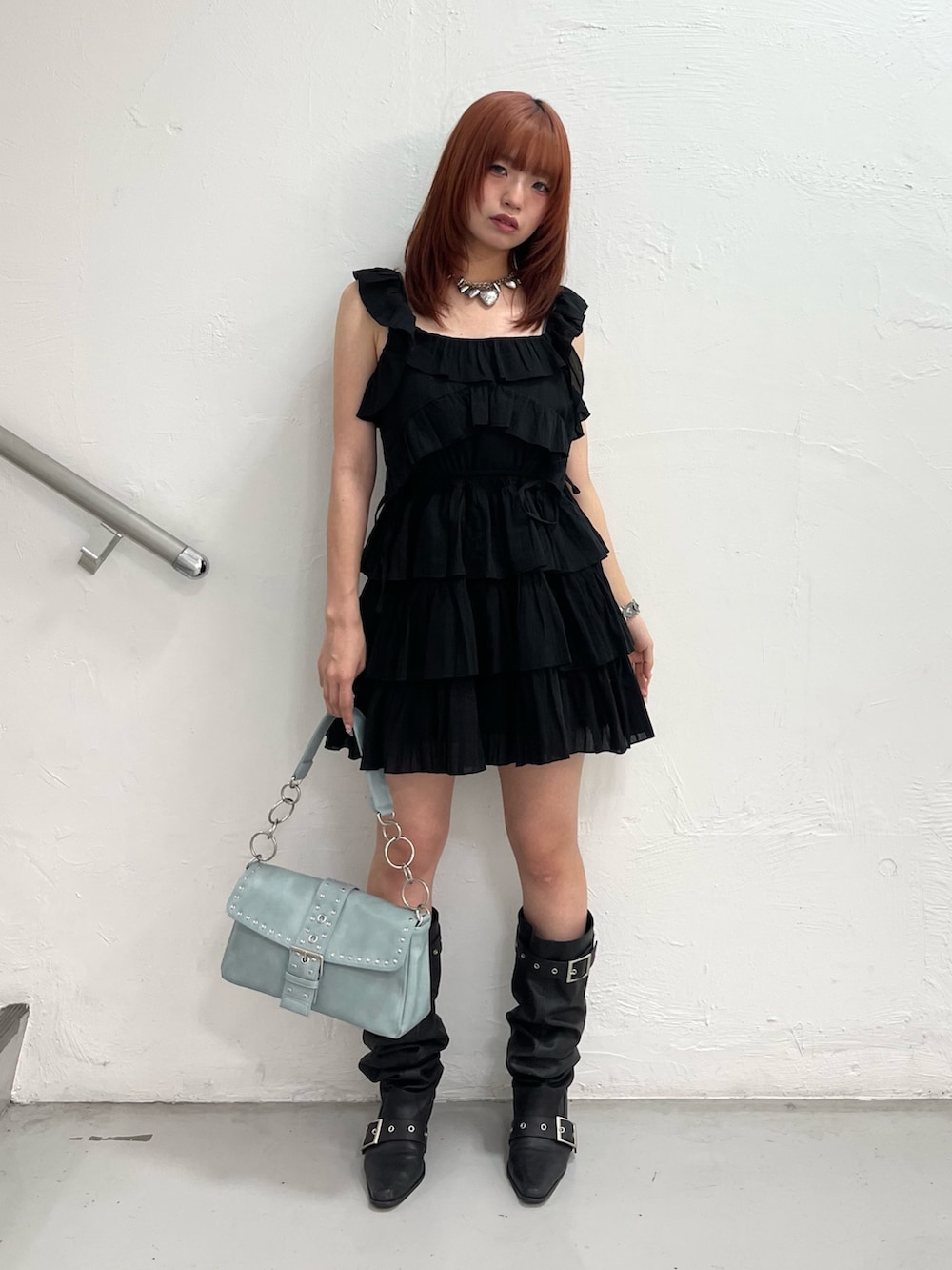 ブラック系のワンピース、ブルー系のハンドバッグ、ブラック系のブーツを着用したレディースの夏コーディネートの2枚目の写真