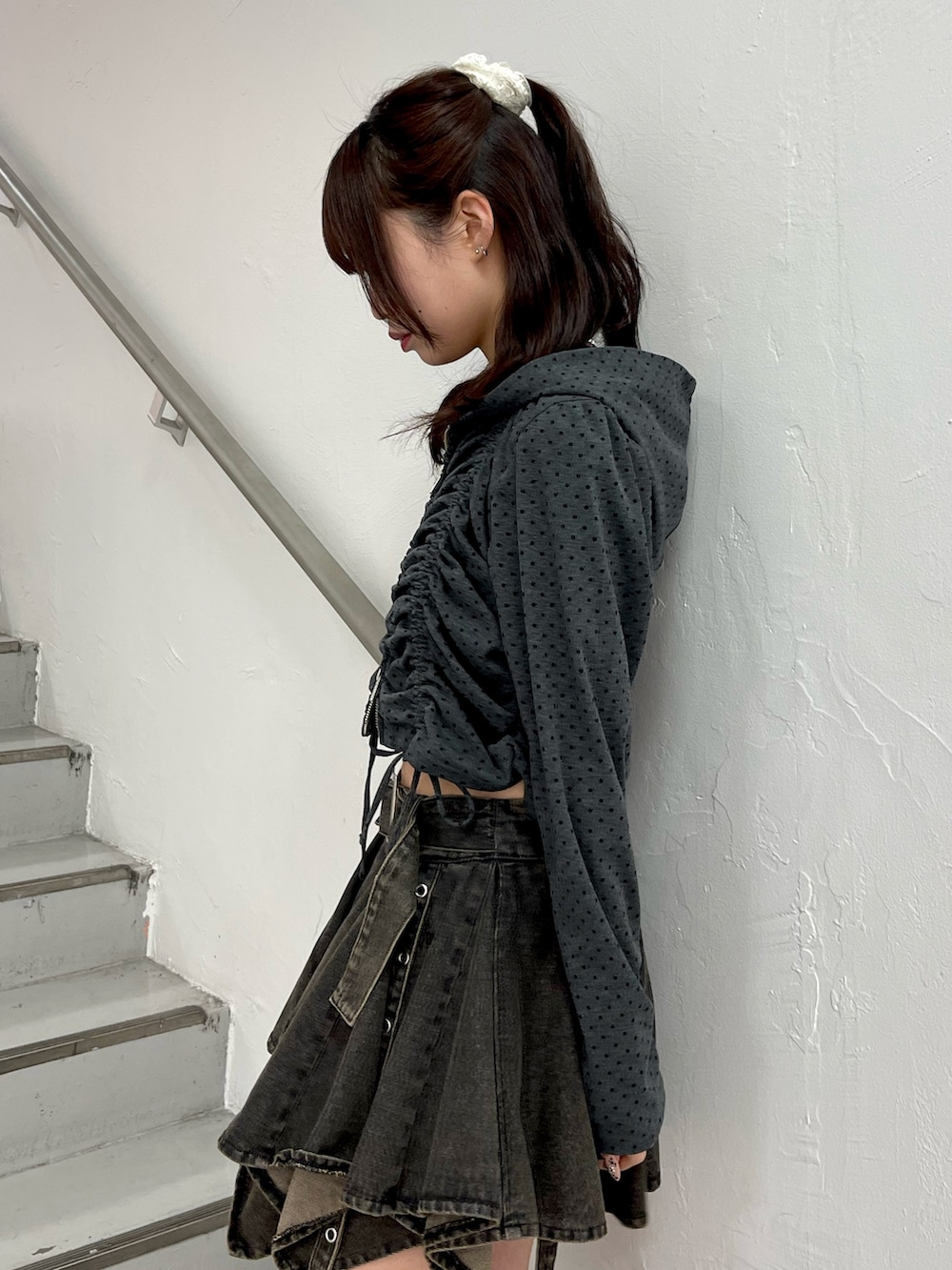 ブラック系のパーカー、ブラック系のデニムスカート、ブラック系のブーツを着用したレディースの春コーディネートの6枚目の写真