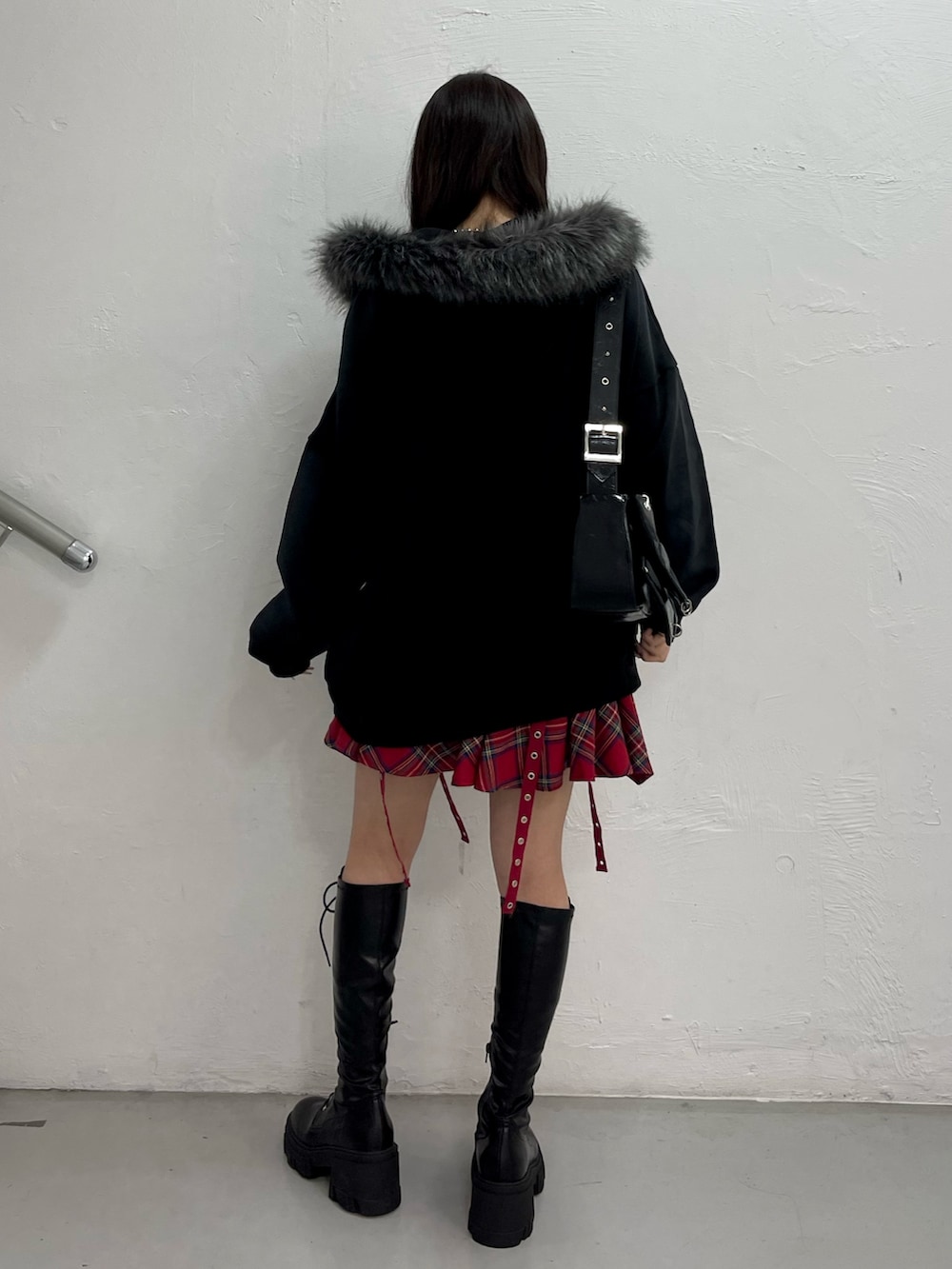 ブラック系のパーカー、レッド系のスカート、ブラック系のショルダーバッグを着用したレディースの冬コーディネートの3枚目の写真