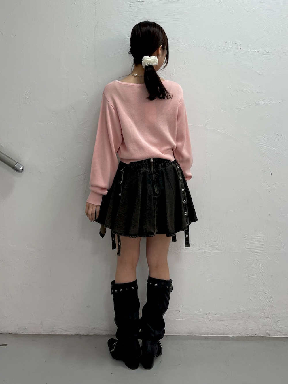 ピンク系のニット/セーター、ブラック系のデニムスカート、ブラック系のブーツを着用したレディースの春コーディネートの4枚目の写真