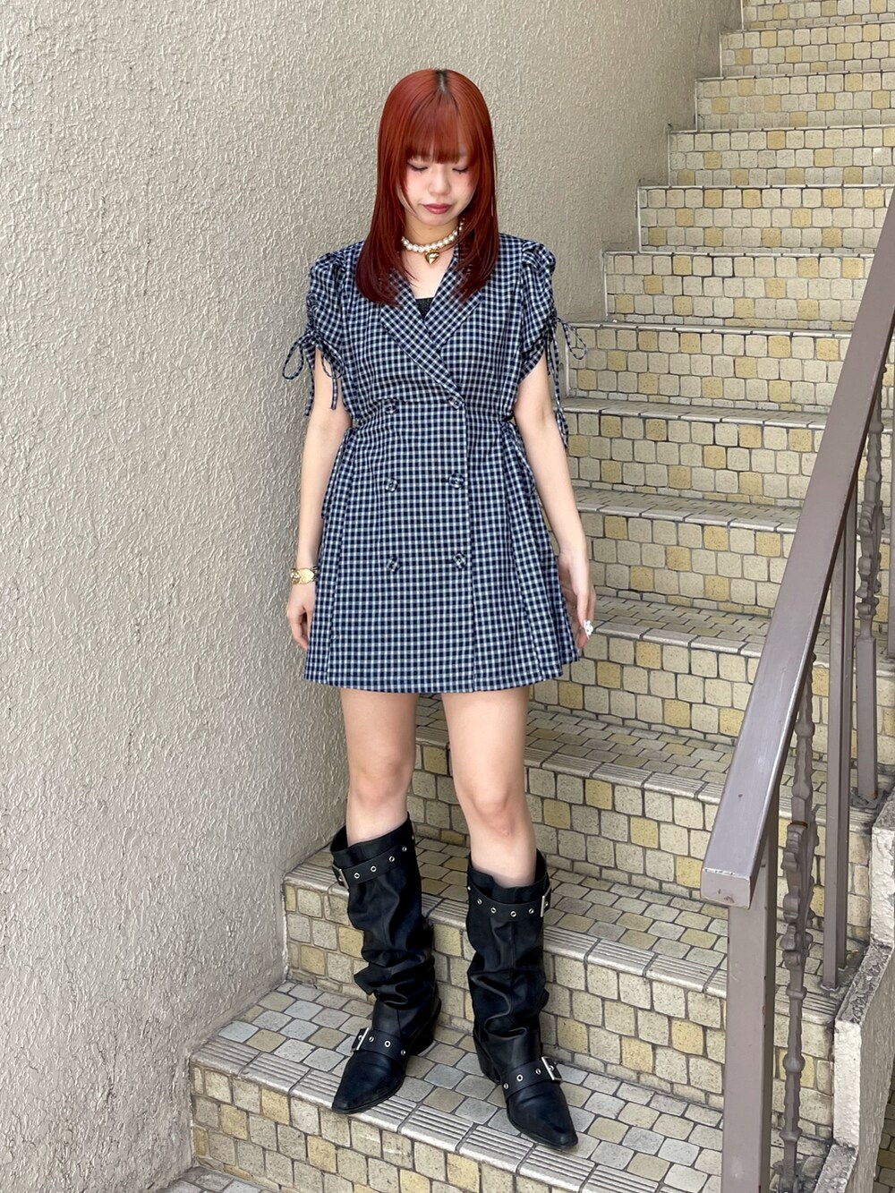 ブルー系のワンピース、ブラック系のブーツ、ゴールド系のネックレスを着用したレディースの春コーディネートの2枚目の写真
