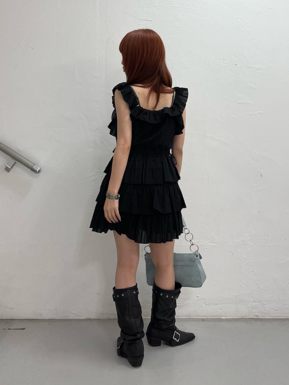 ブラック系のワンピース、ブルー系のハンドバッグ、ブラック系のブーツを着用したレディースの夏コーディネートの4枚目の写真