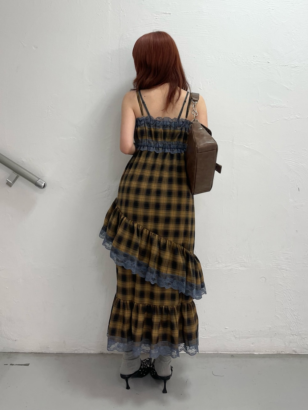 イエロー系のワンピース、ブラック系のパンプス、ブラウン系のハンドバッグを着用したレディースの夏コーディネートの4枚目の写真