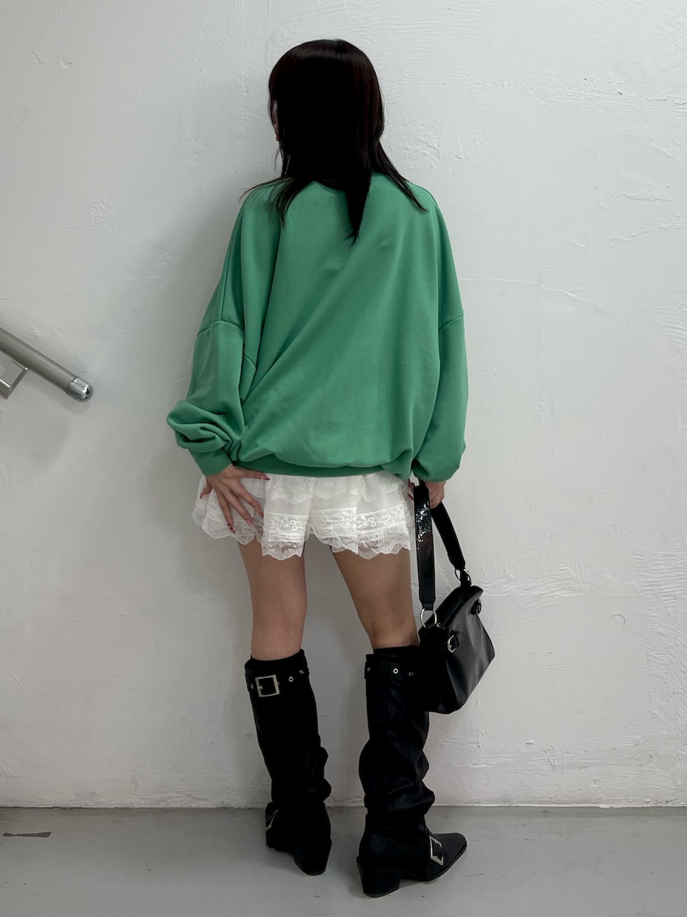 グリーン系のスウェット、ホワイト系のその他パンツ、ブラック系のハンドバッグを着用したレディースの冬コーディネートの4枚目の写真