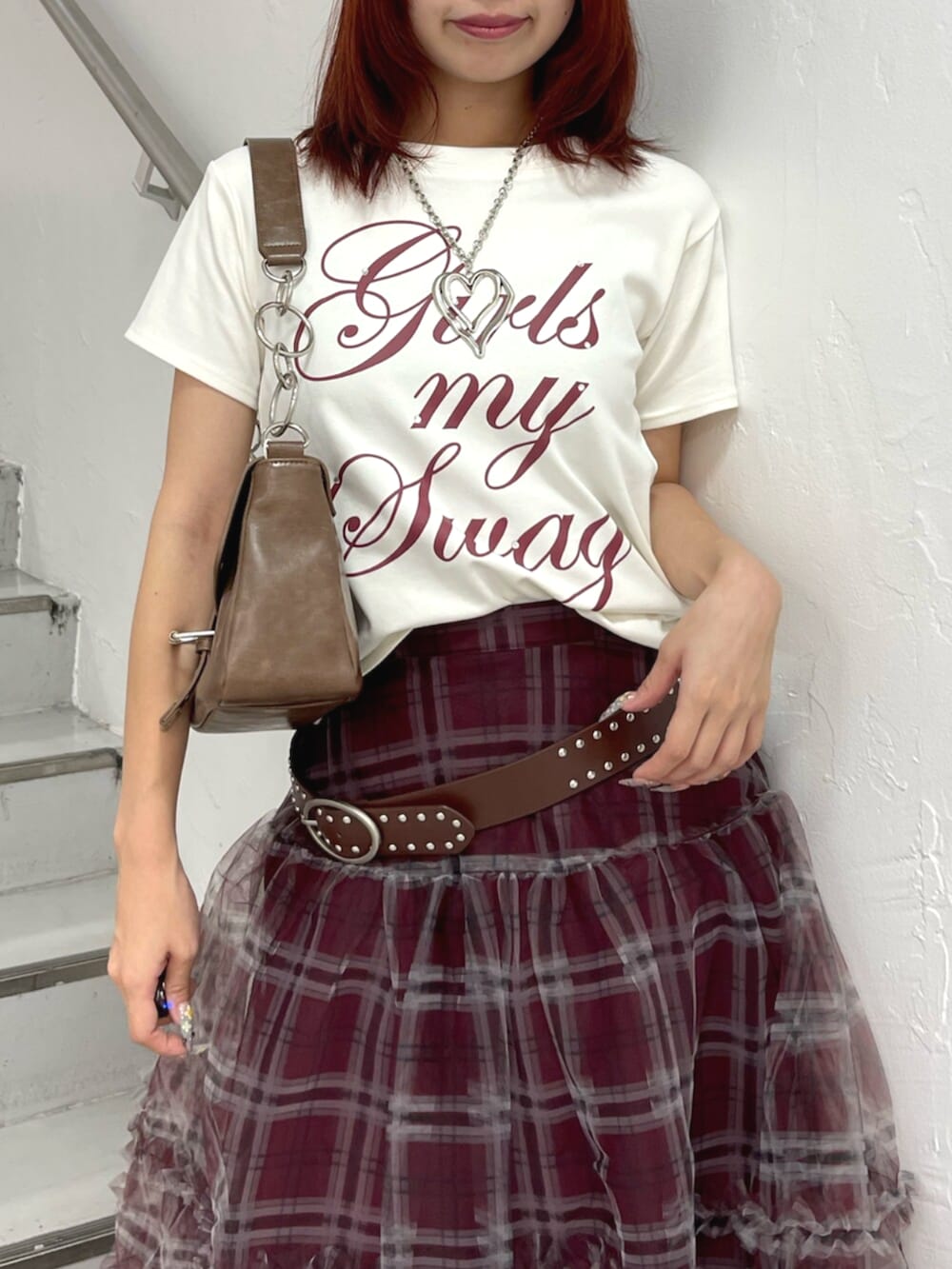 ブラウン系のハンドバッグ、ブラック系のブーツ、ホワイト系のTシャツ/カットソーを着用したレディースの夏コーディネートの5枚目の写真