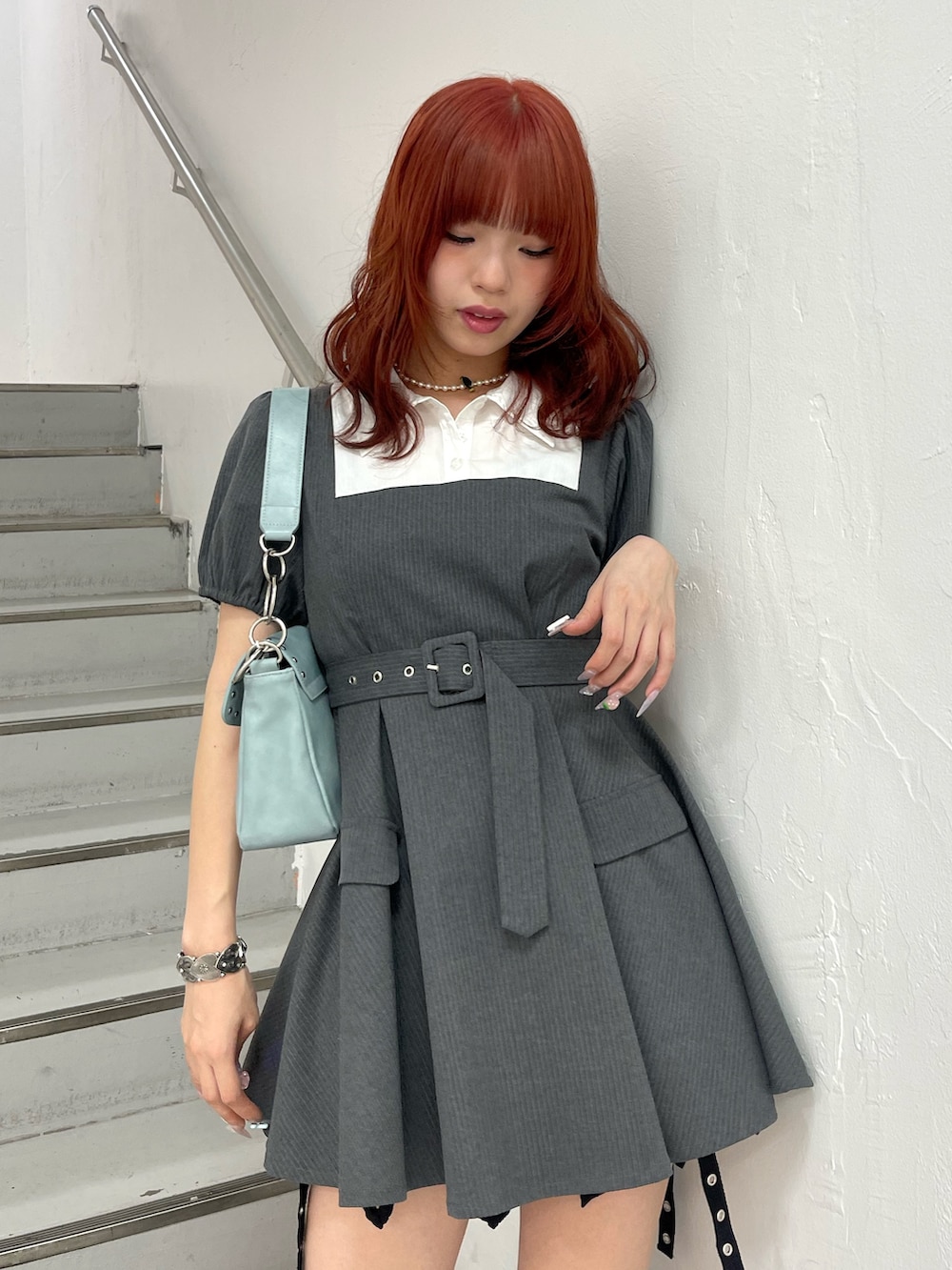 グレー系のワンピース、ブルー系のハンドバッグ、ブラック系のブーツを着用したレディースの夏コーディネートの5枚目の写真
