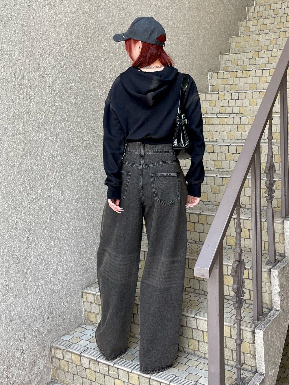 ブラック系のパーカー、ブラック系のデニムパンツ、ブラック系のハンドバッグを着用したレディースの春コーディネートの4枚目の写真