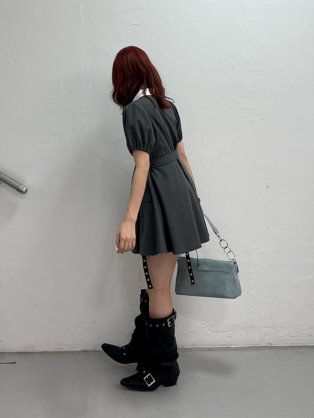 グレー系のワンピース、ブルー系のハンドバッグ、ブラック系のブーツを着用したレディースの夏コーディネートの3枚目の写真