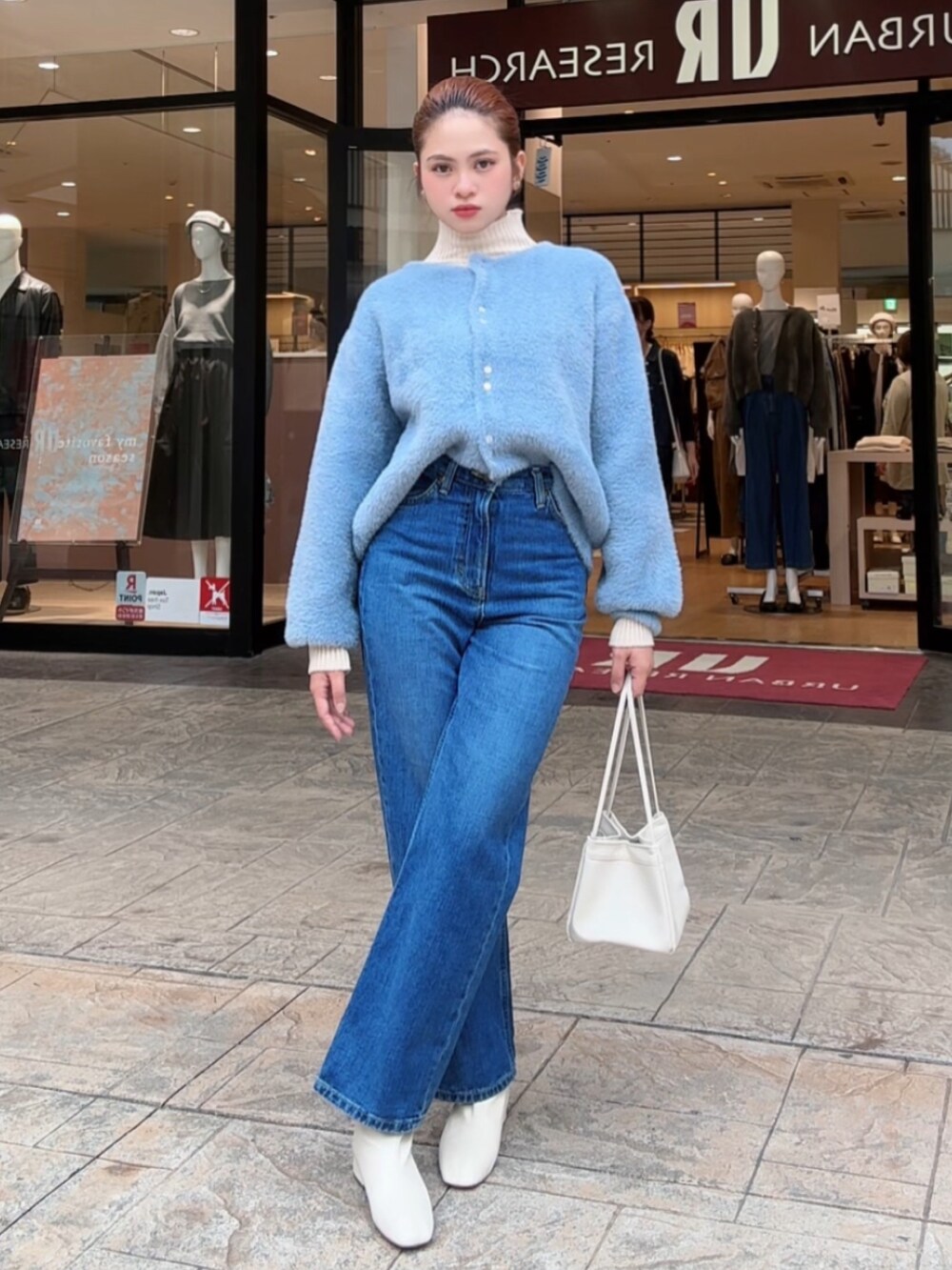 ブルー系のカーディガン/ボレロ、ホワイト系のニット/セーター、ブルー系のデニムパンツを着用したレディースの秋コーディネートの5枚目の写真