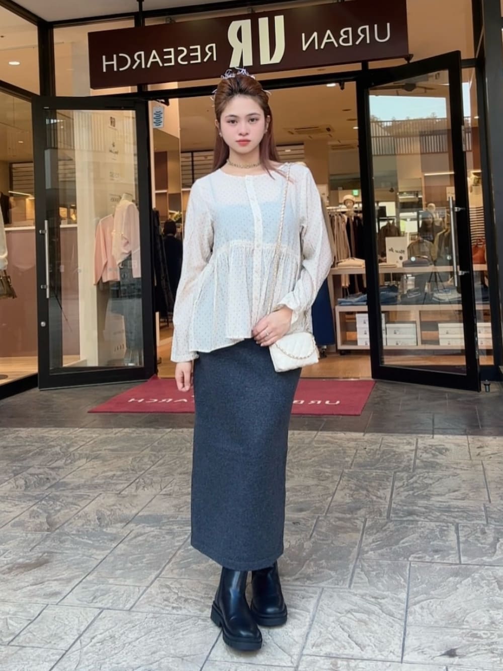 グレー系のスカート、ベージュ系のシャツ/ブラウス、ブラック系のブーツを着用したレディースの秋コーディネートの3枚目の写真