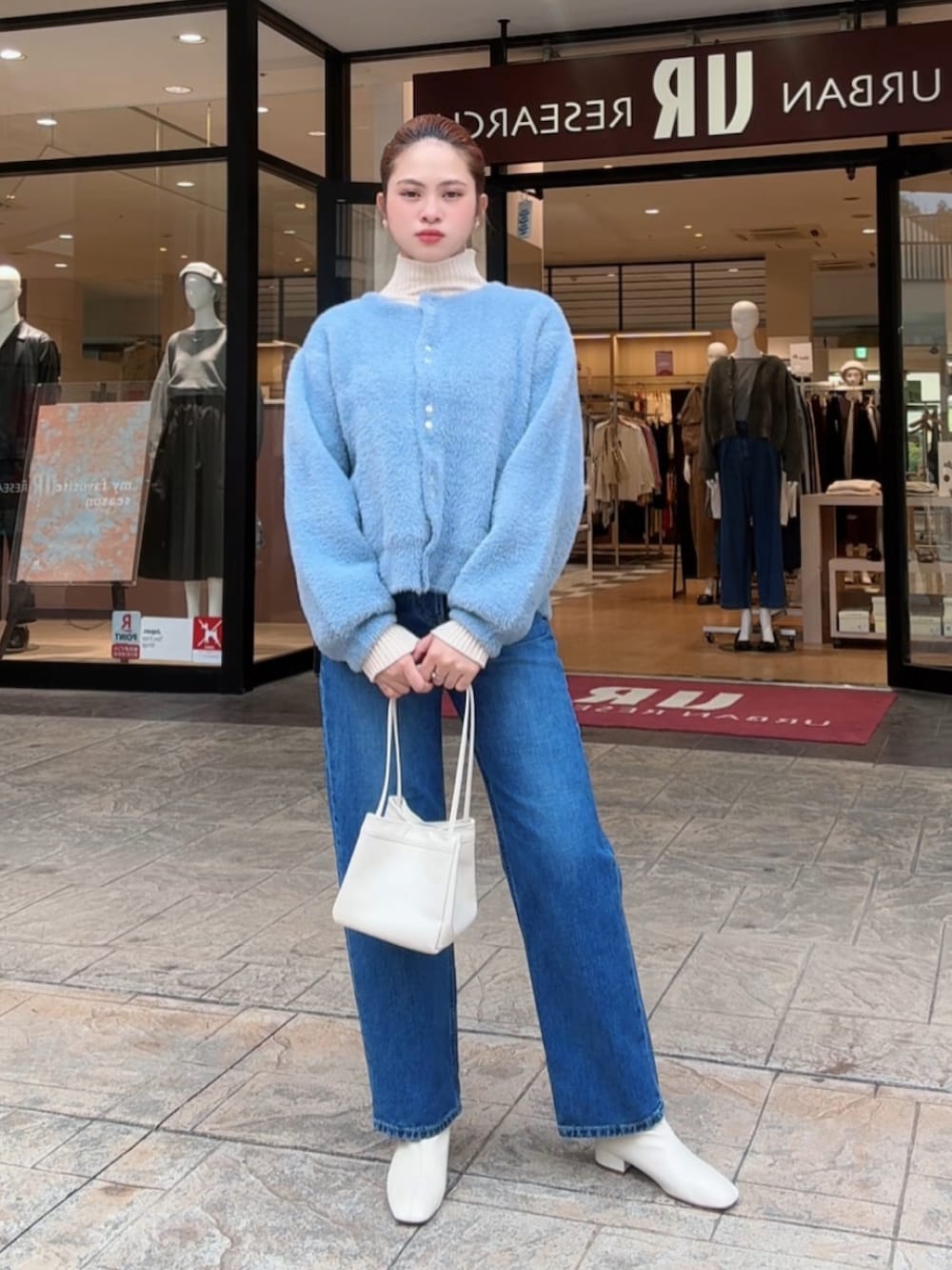 ブルー系のカーディガン/ボレロ、ホワイト系のニット/セーター、ブルー系のデニムパンツを着用したレディースの秋コーディネートの3枚目の写真
