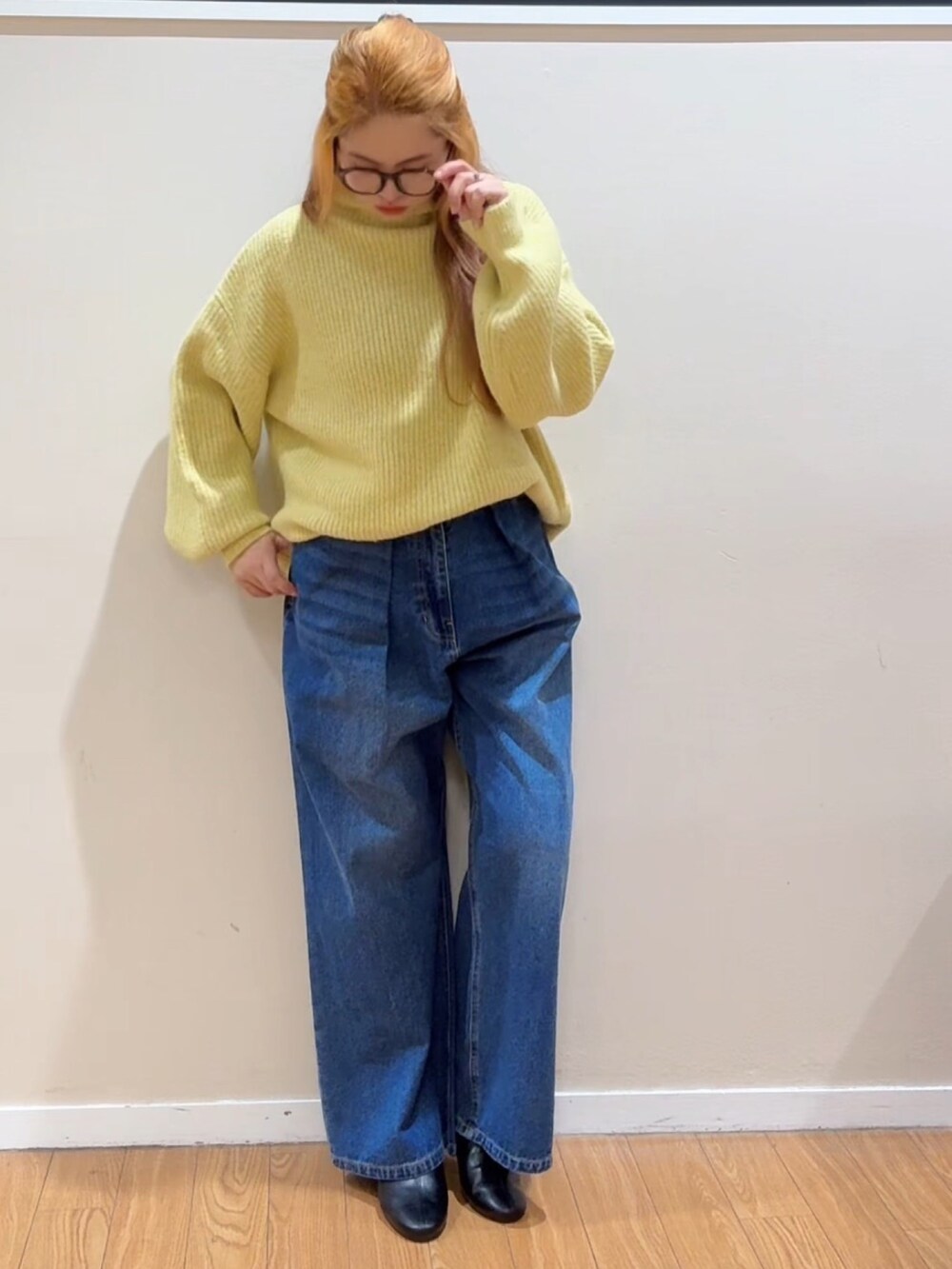 イエロー系のニット/セーター、ブルー系のデニムパンツ、ブラック系のブーツを着用したレディースの冬コーディネートの2枚目の写真