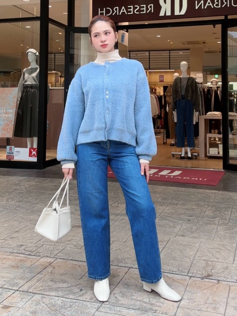 ブルー系のカーディガン/ボレロ、ホワイト系のニット/セーター、ブルー系のデニムパンツを着用したレディースの秋コーディネートの4枚目の写真