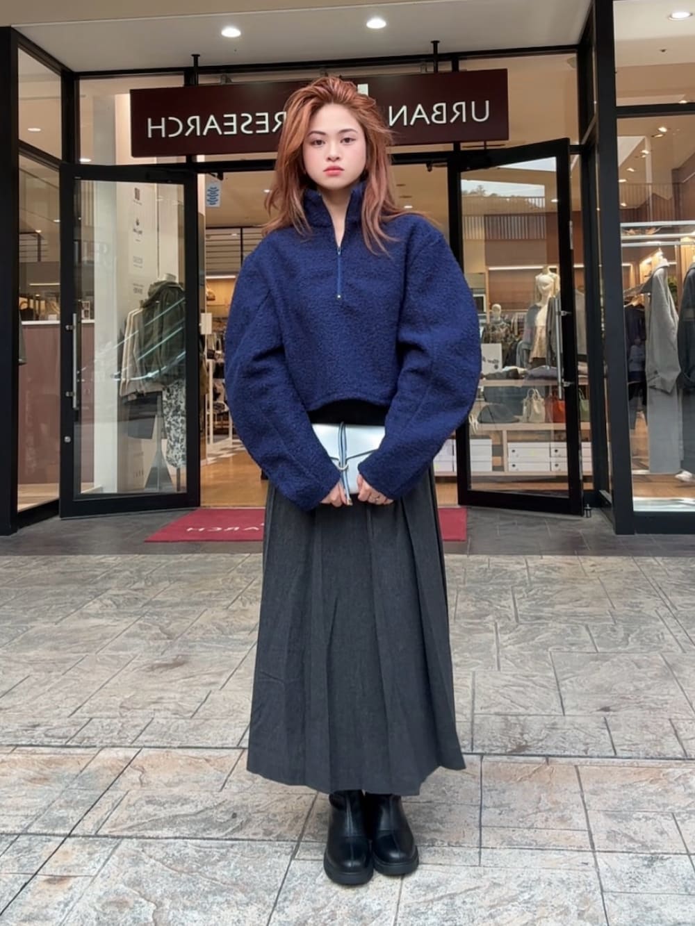 グレー系のショルダーバッグ、ブラック系のスカート、ブラック系のブーツを着用したレディースの秋コーディネートの2枚目の写真