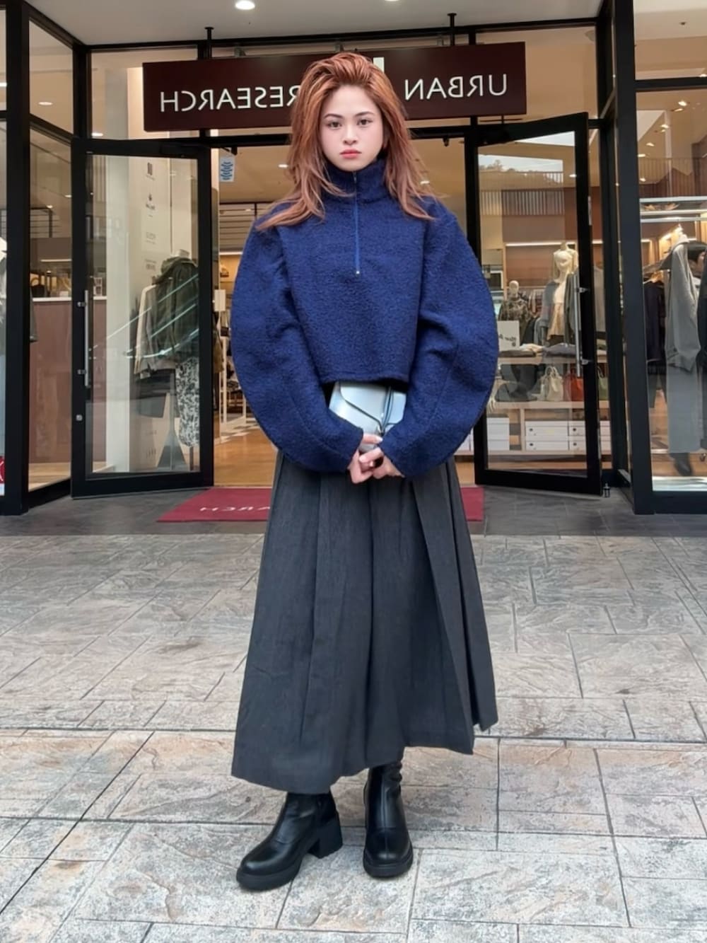 グレー系のショルダーバッグ、ブラック系のスカート、ブラック系のブーツを着用したレディースの秋コーディネートの3枚目の写真