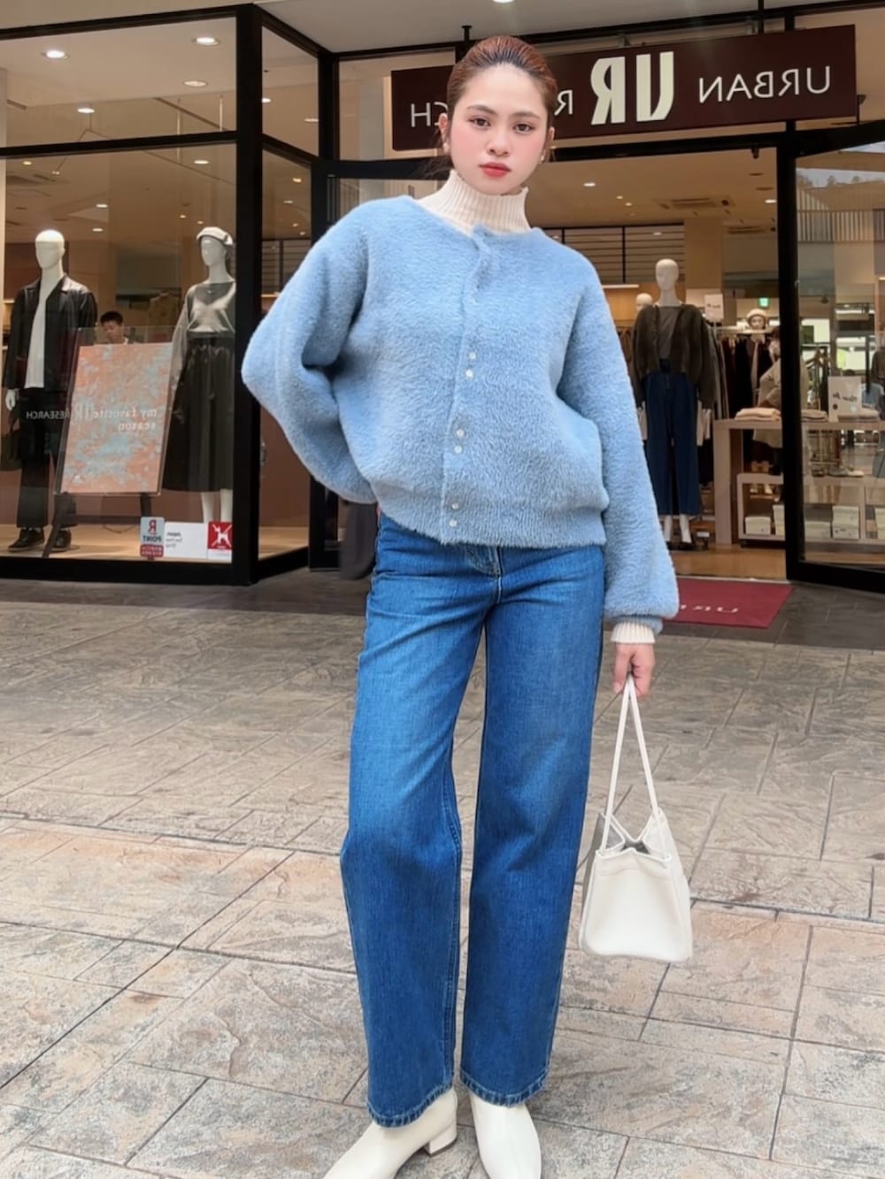 ブルー系のカーディガン/ボレロ、ホワイト系のニット/セーター、ブルー系のデニムパンツを着用したレディースの秋コーディネートの2枚目の写真
