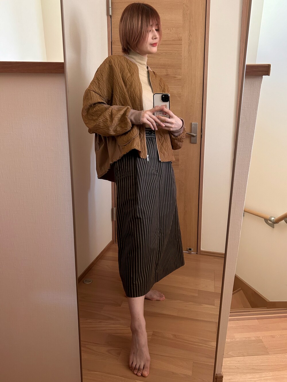 イエロー系のジャケット/アウター、ベージュ系のニット/セーター、ブラウン系のスカートを着用したレディースの秋コーディネートの2枚目の写真