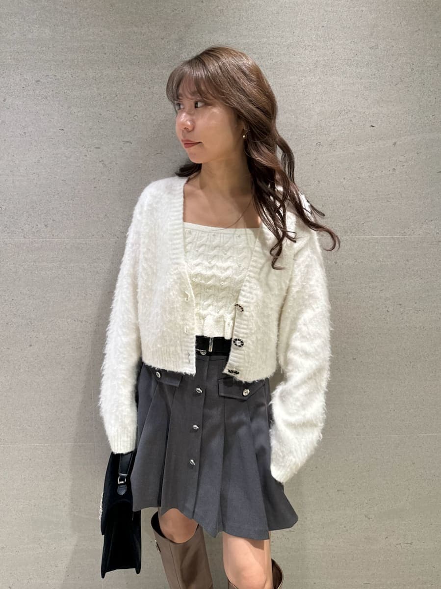 イエロー系のブーツ、ホワイト系のアンサンブル、ブラック系のハンドバッグを着用したレディースの秋コーディネートの5枚目の写真