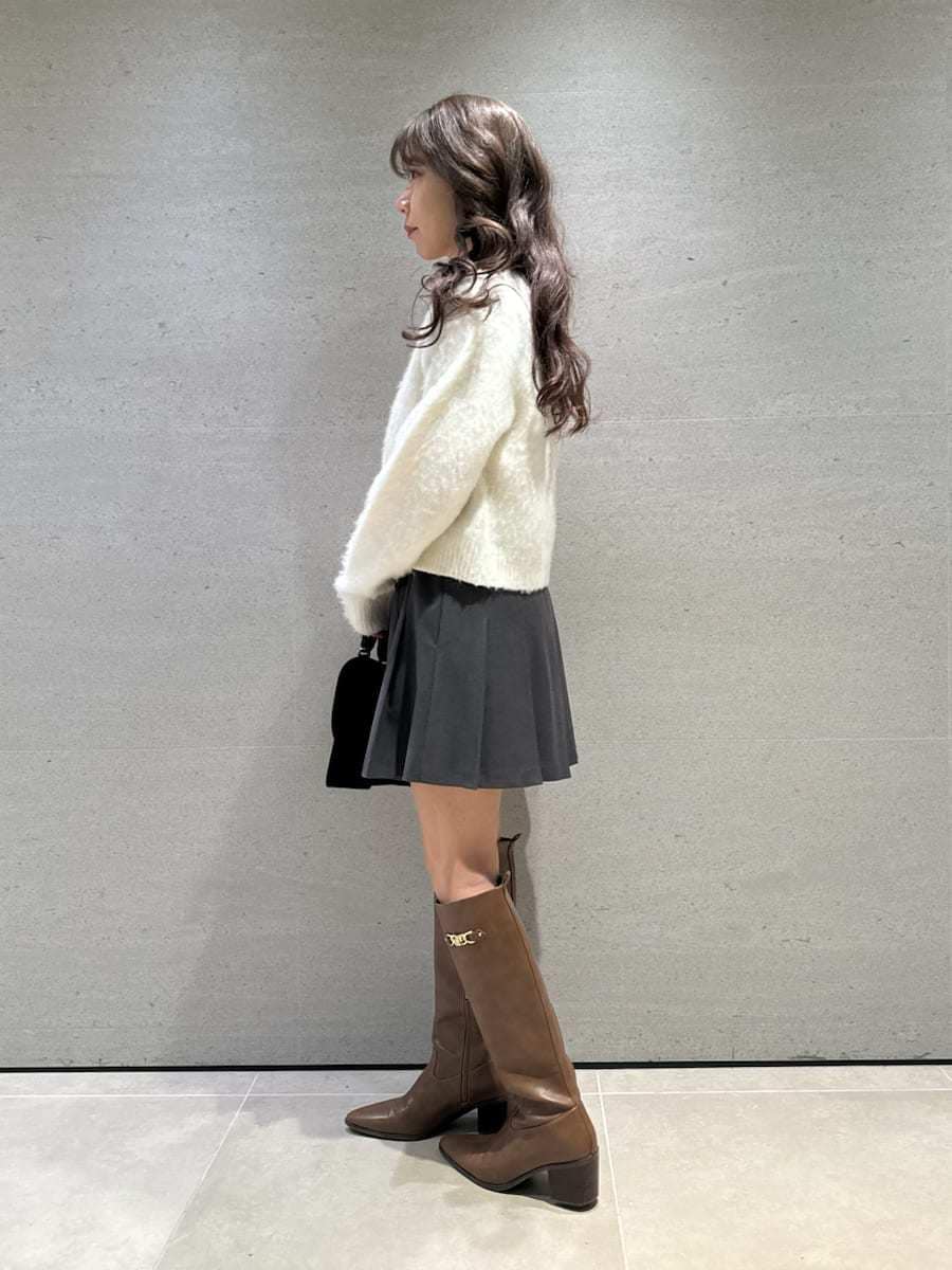 イエロー系のブーツ、ホワイト系のアンサンブル、ブラック系のハンドバッグを着用したレディースの秋コーディネートの3枚目の写真