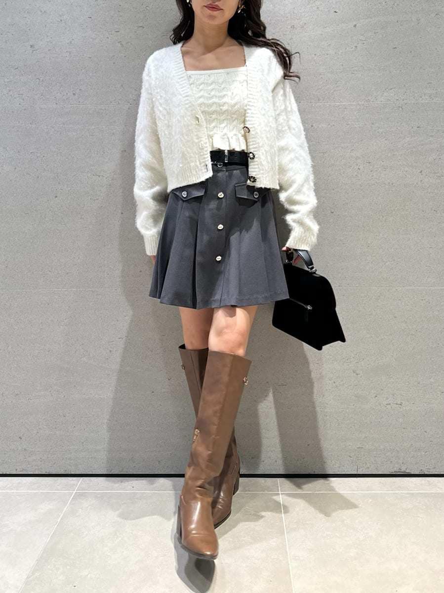 イエロー系のブーツ、ホワイト系のアンサンブル、ブラック系のハンドバッグを着用したレディースの秋コーディネートの2枚目の写真