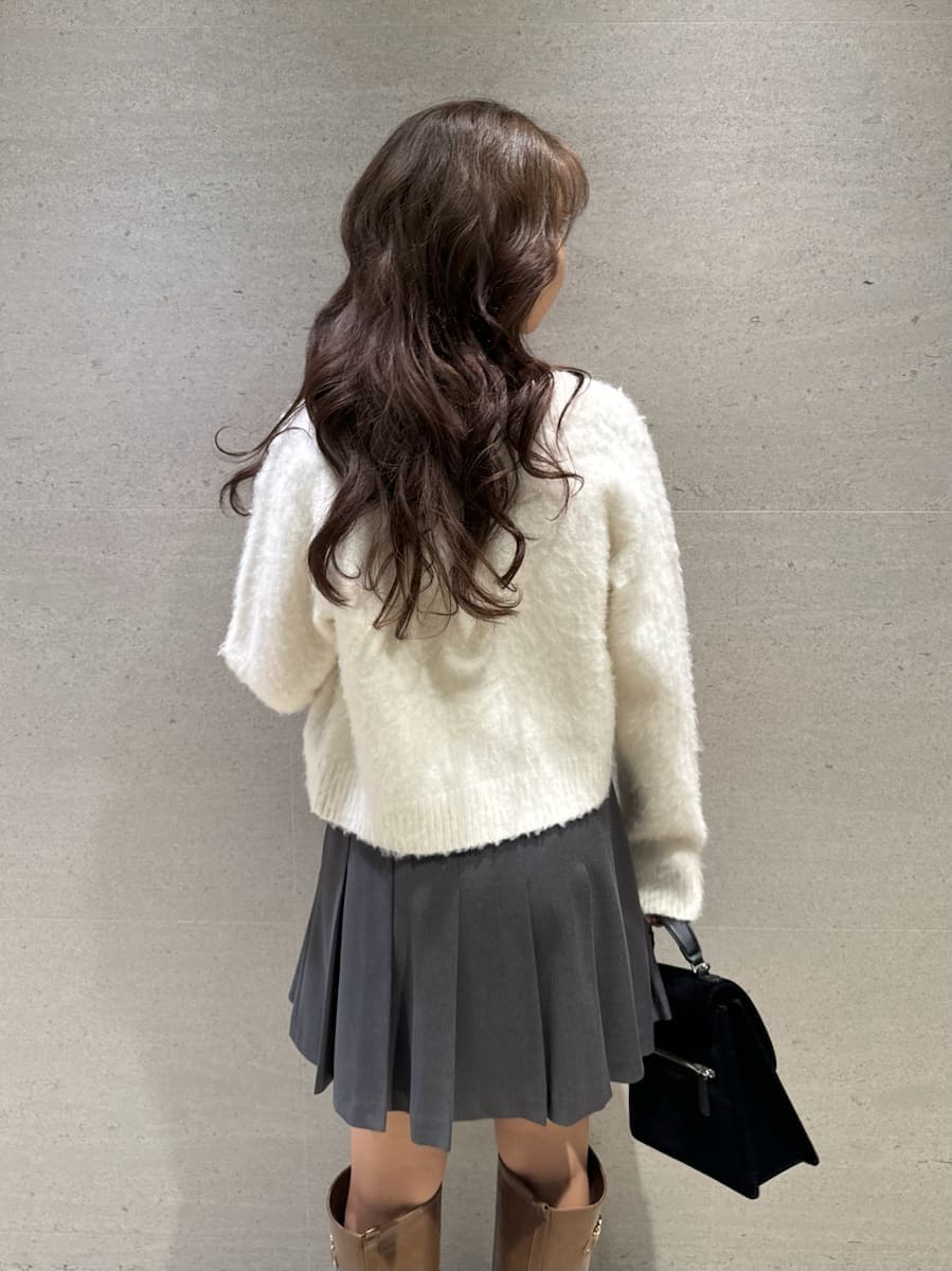 イエロー系のブーツ、ホワイト系のアンサンブル、ブラック系のハンドバッグを着用したレディースの秋コーディネートの7枚目の写真