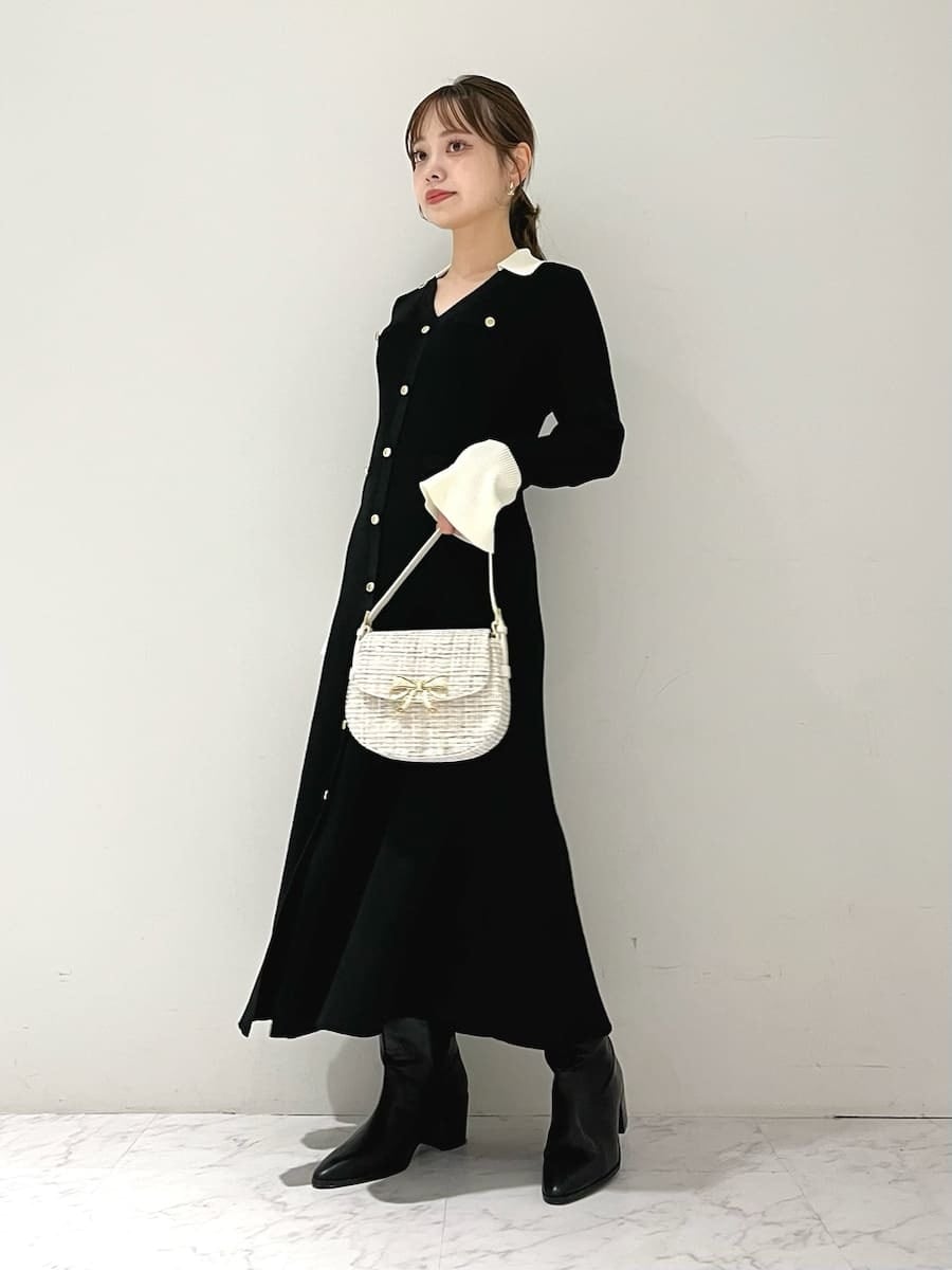 ブラック系のワンピース、ブラック系のブーツ、ホワイト系のハンドバッグを着用したレディースの秋コーディネートの3枚目の写真