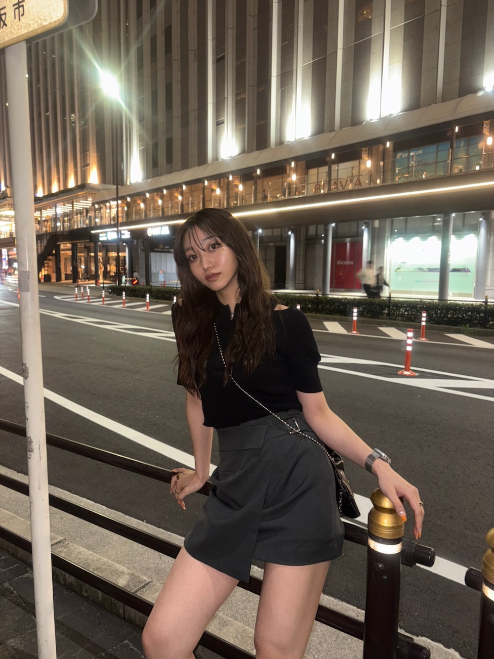 ブラック系のニット/セーター、ブラック系のショルダーバッグ、グレー系のスカートを着用したレディースの春コーディネートの2枚目の写真