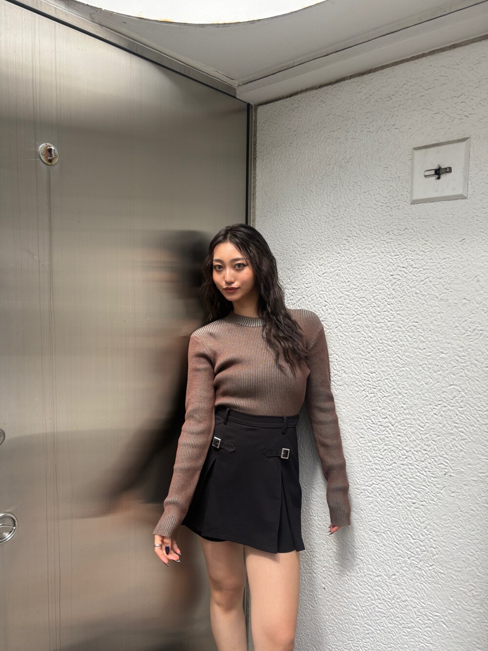 ブラウン系のニット/セーター、ブラック系のブーツを着用したレディースの秋コーディネートの3枚目の写真