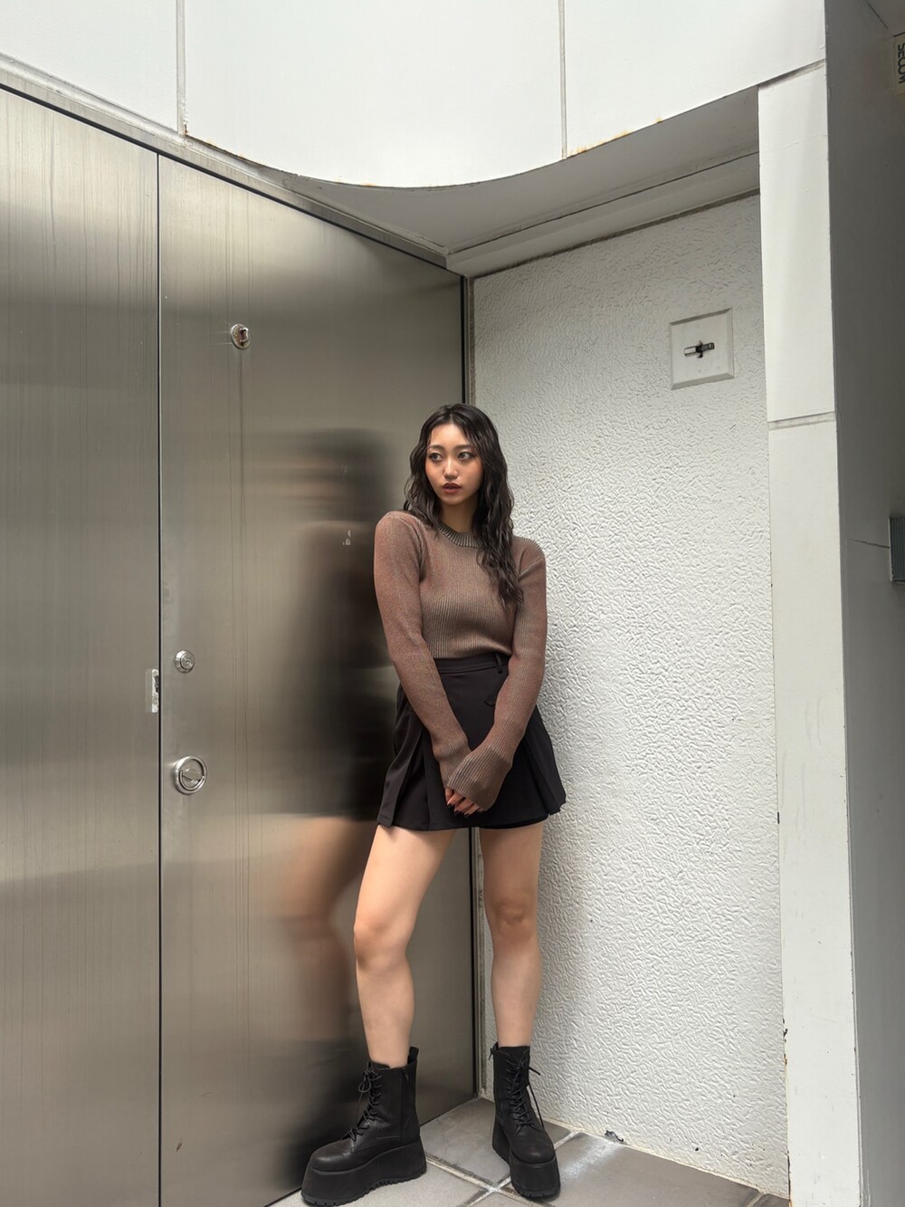 ブラウン系のニット/セーター、ブラック系のブーツを着用したレディースの秋コーディネートの2枚目の写真