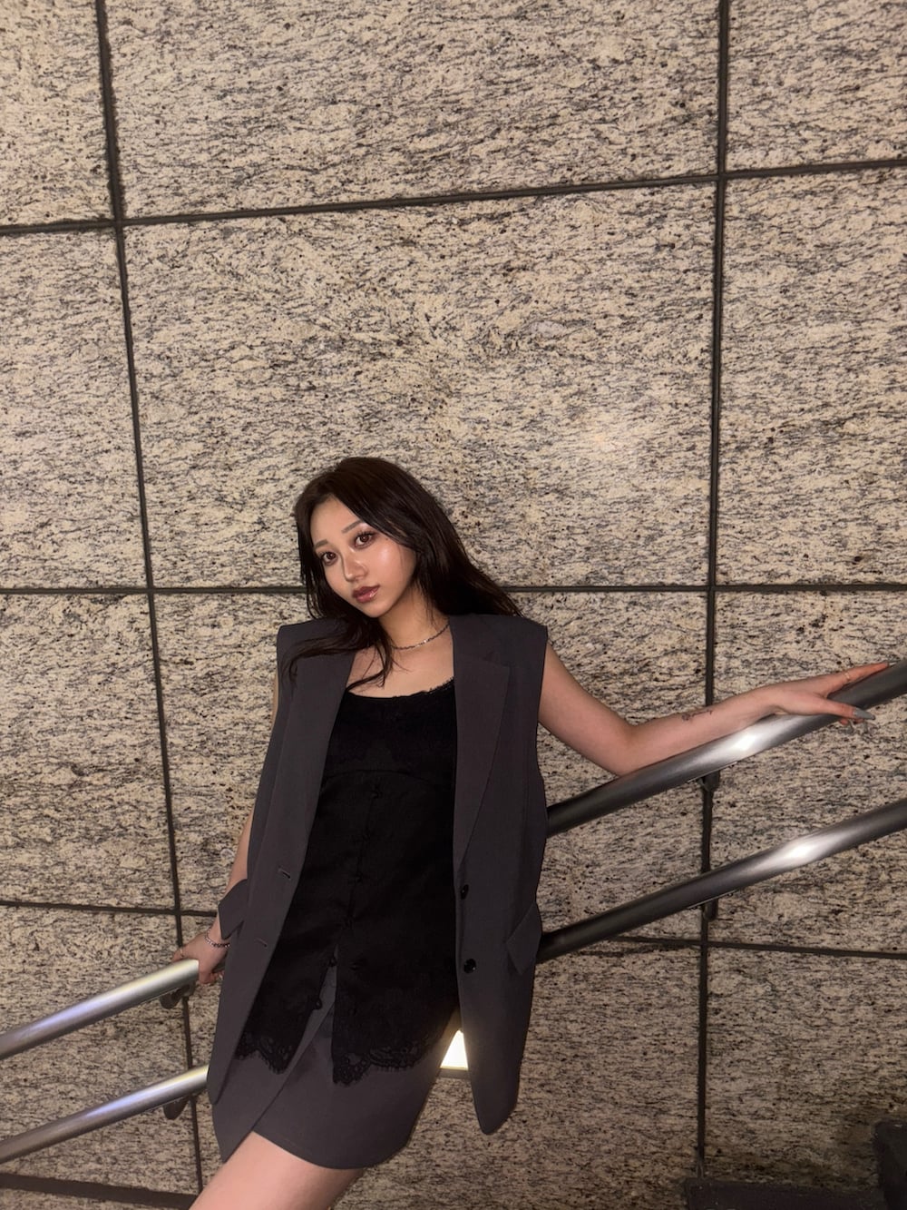 グレー系のベスト、ブラック系のキャミソール、グレー系のスカートを着用したレディースの春コーディネートの3枚目の写真