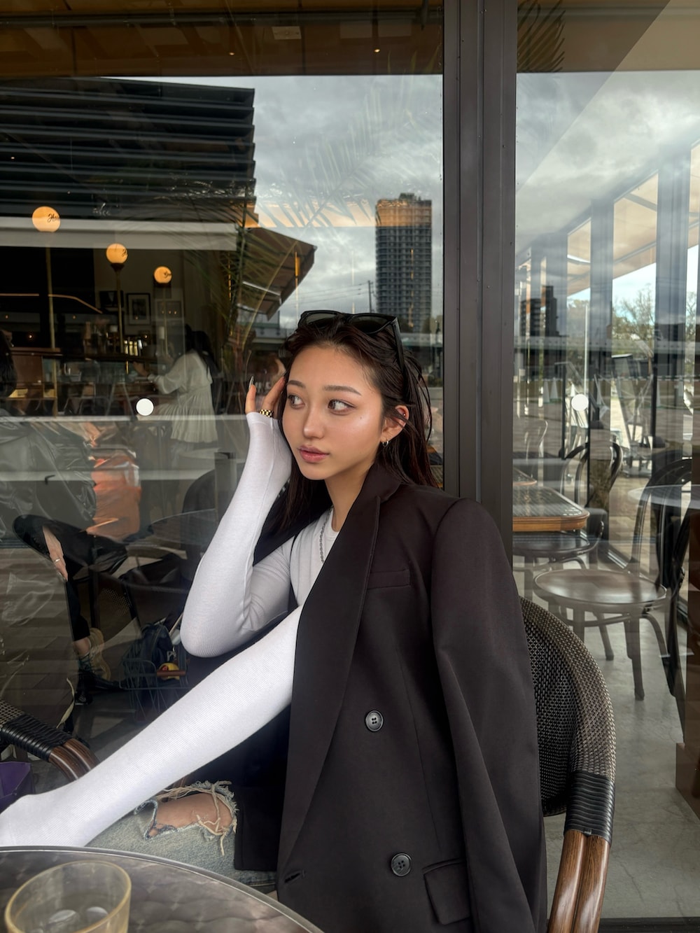 ブラック系のテーラードジャケット、ブルー系のデニムパンツを着用したレディースの春コーディネートの2枚目の写真