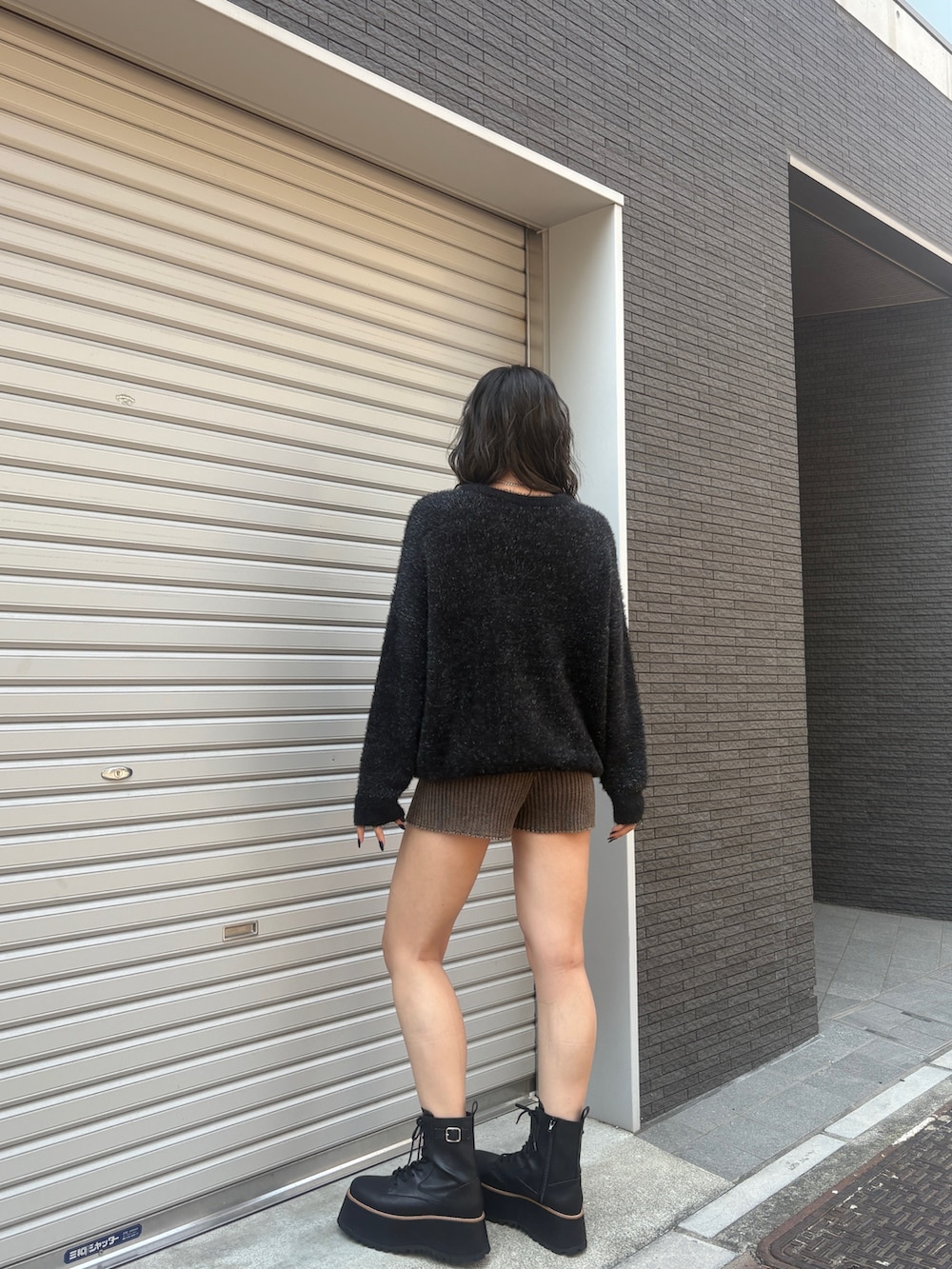 ブラック系のニット/セーター、ブラウン系のその他パンツ、ブラック系のブーツを着用したレディースの秋コーディネートの3枚目の写真