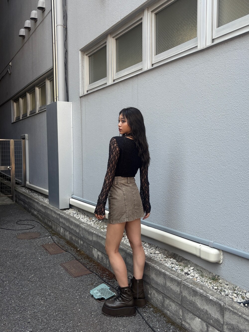 ブラック系のTシャツ/カットソー、グレー系のスカート、ブラウン系のブーツを着用したレディースの秋コーディネートの3枚目の写真