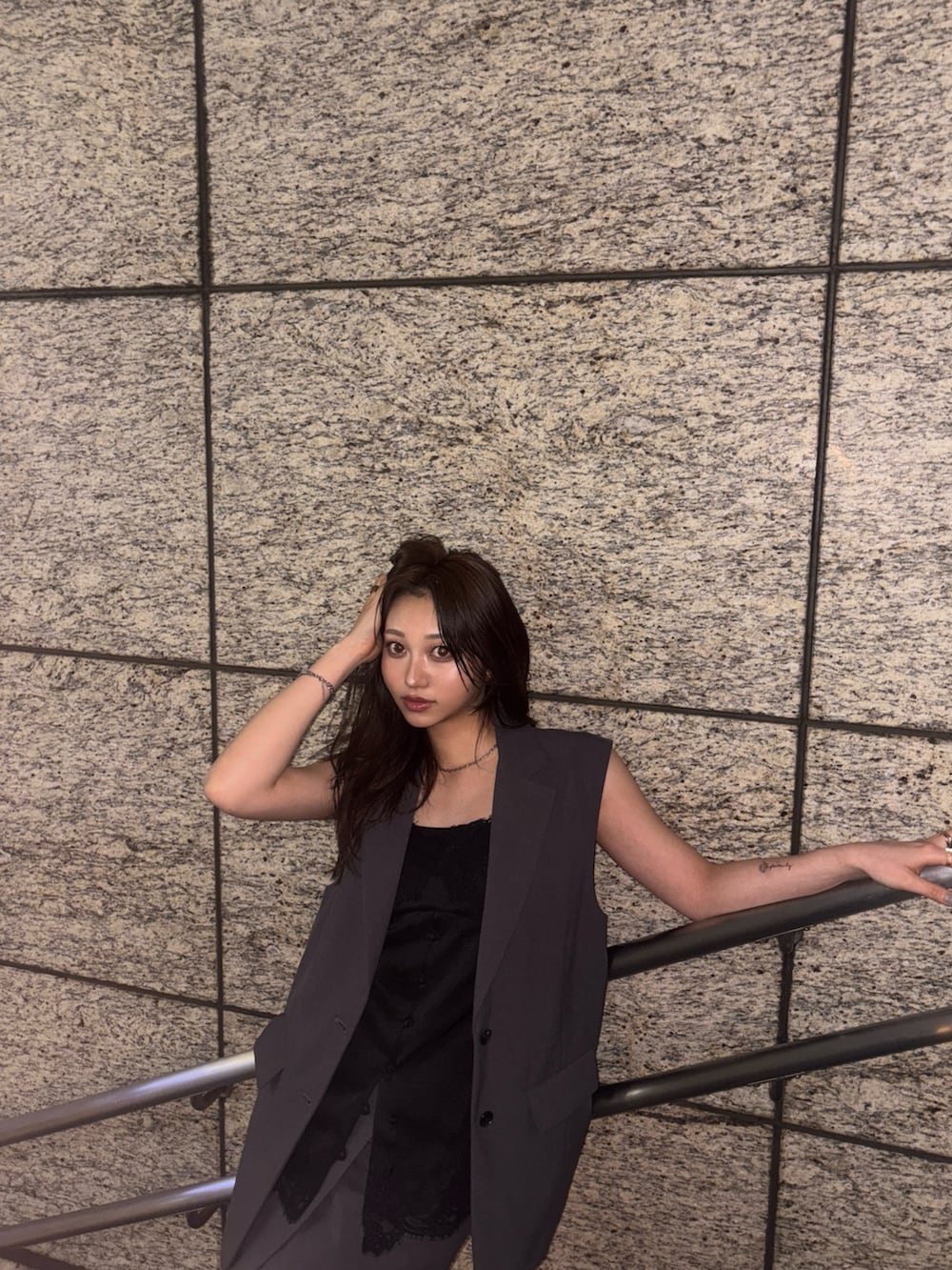 グレー系のベスト、ブラック系のキャミソール、グレー系のスカートを着用したレディースの春コーディネートの2枚目の写真