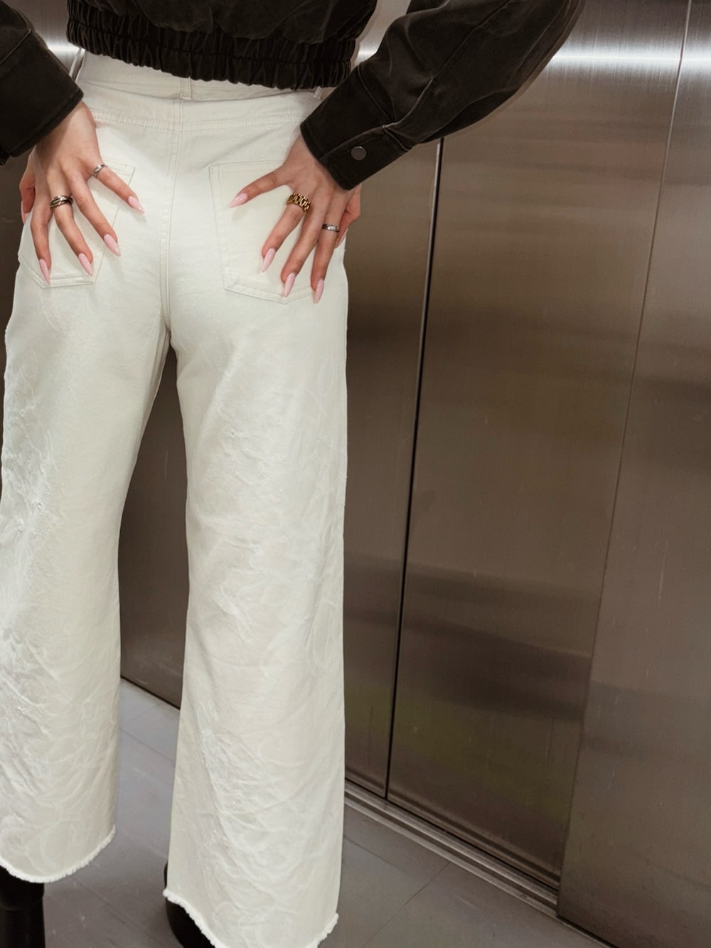 ブラック系のブルゾン、ホワイト系のデニムパンツを着用したレディースの冬コーディネートの2枚目の写真