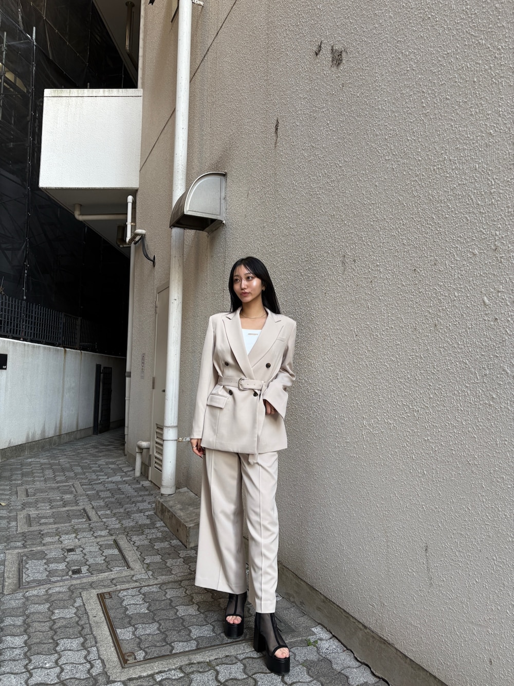 ホワイト系のキャミソール、ベージュ系のテーラードジャケット、ベージュ系のスラックスを着用したレディースの冬コーディネートの2枚目の写真