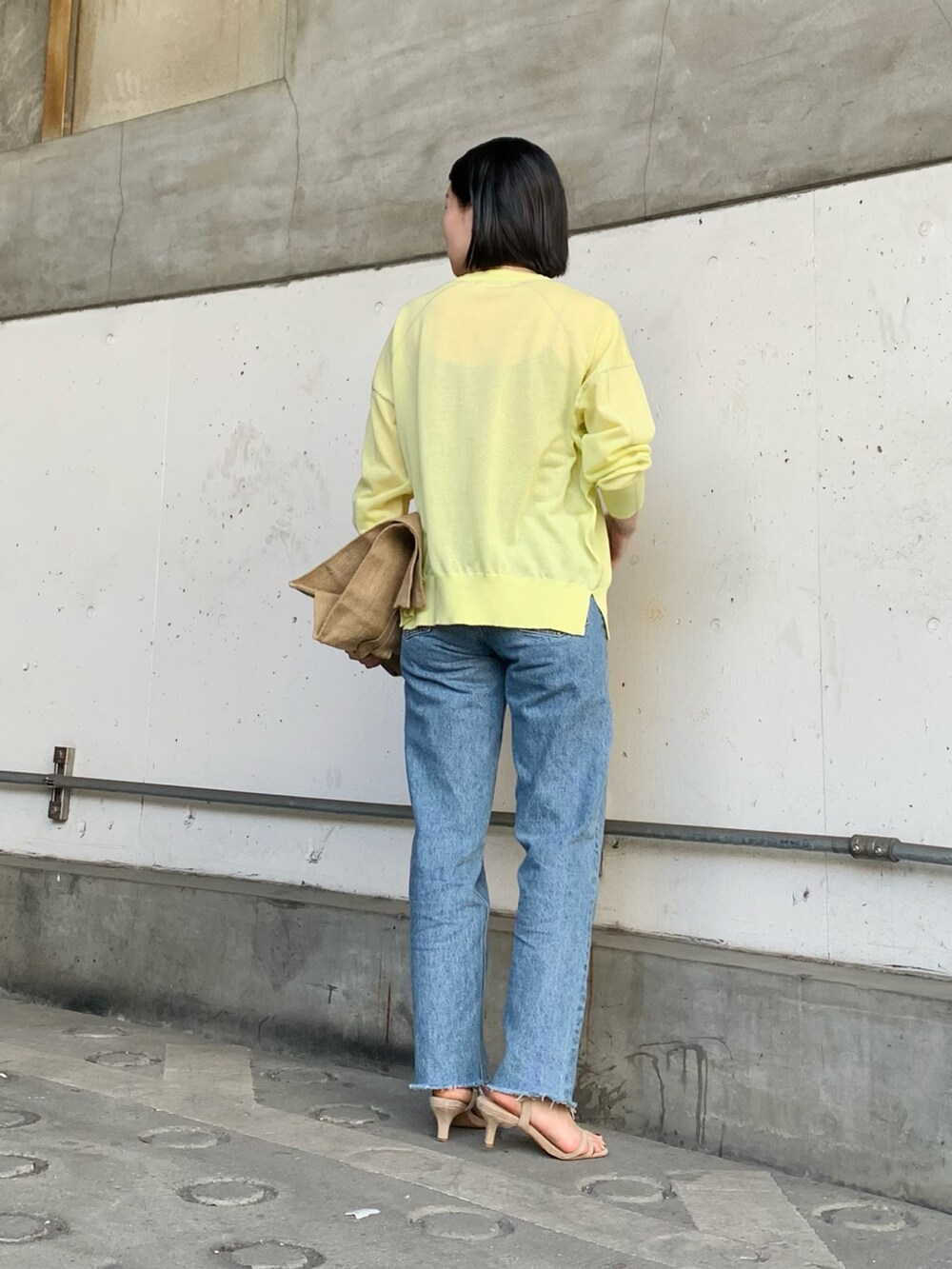 イエロー系のカーディガン/ボレロ、ブルー系のデニムパンツ、ベージュ系のキャミソールを着用したレディースの春コーディネートの3枚目の写真